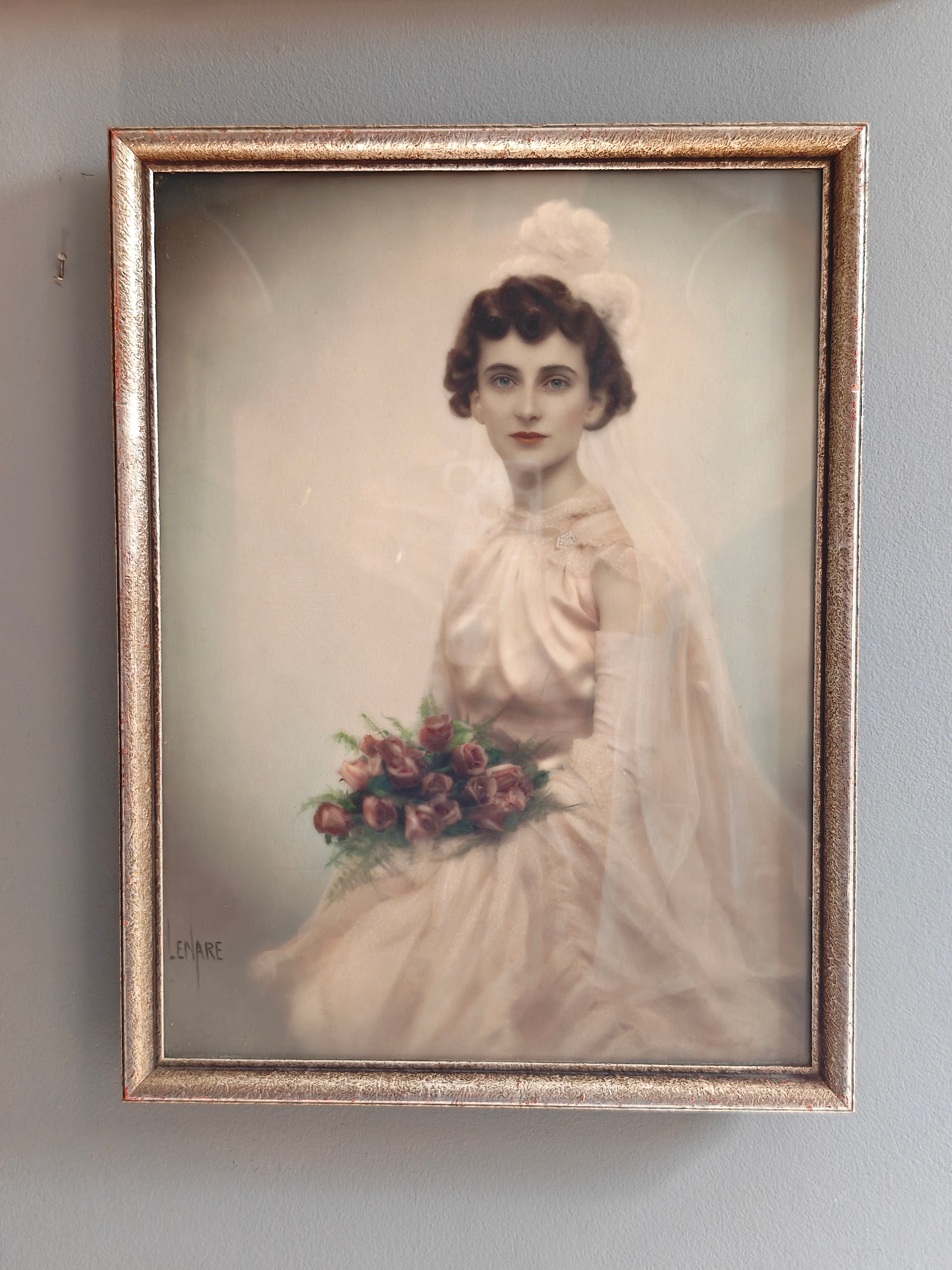 A vintage framed portrait print of a woman in a white bridal gown holding a bouquet of pink and red flowers, set in an ornate gold-toned frame.