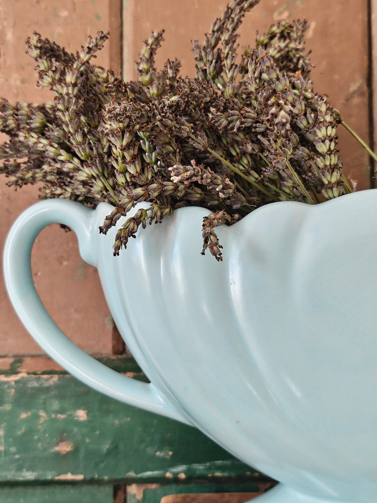 Close up of the handle of a large pale blue mantle vase with fluted form