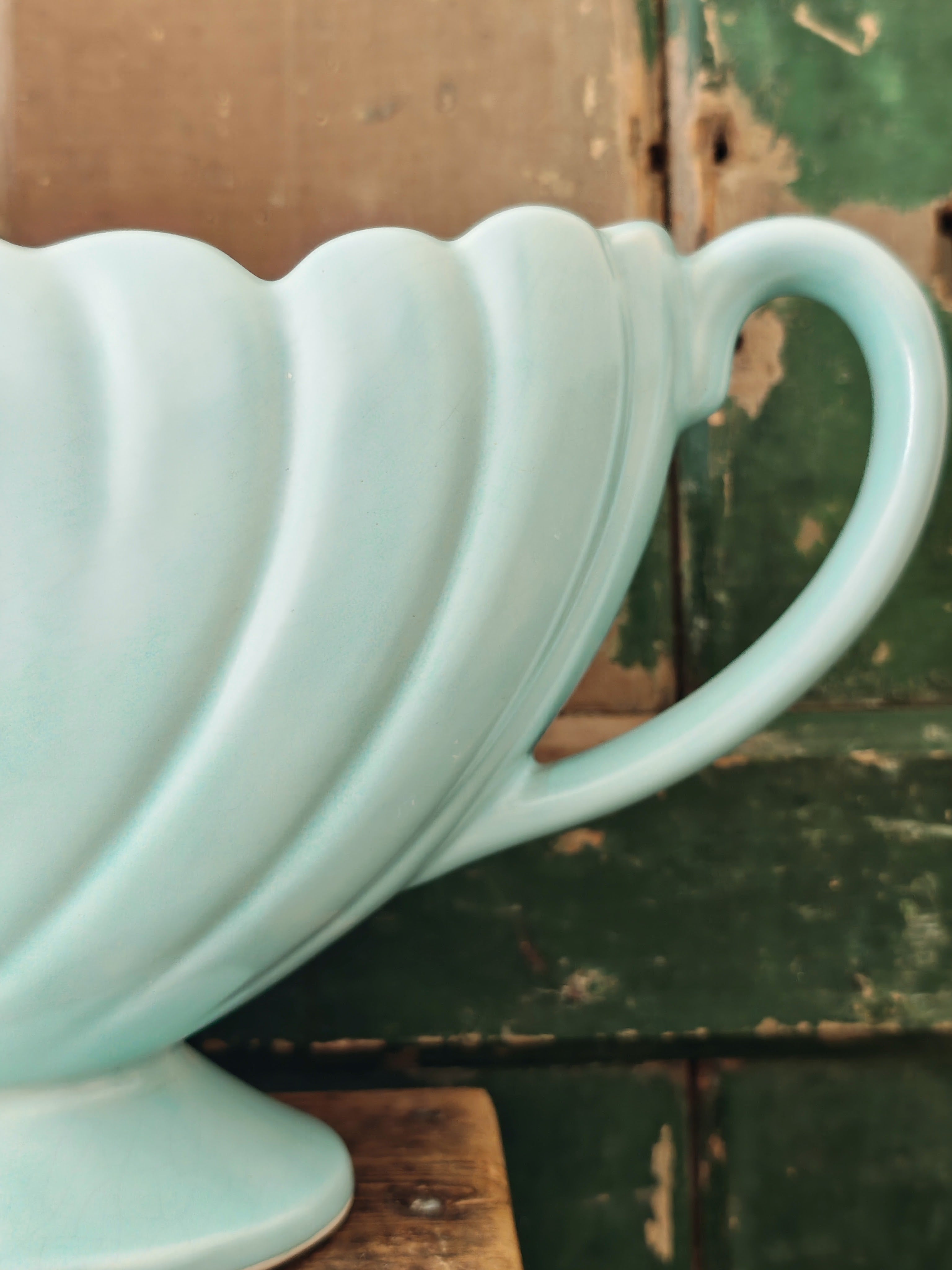 Close up of the handle of a large pale blue mantle vase with fluted form