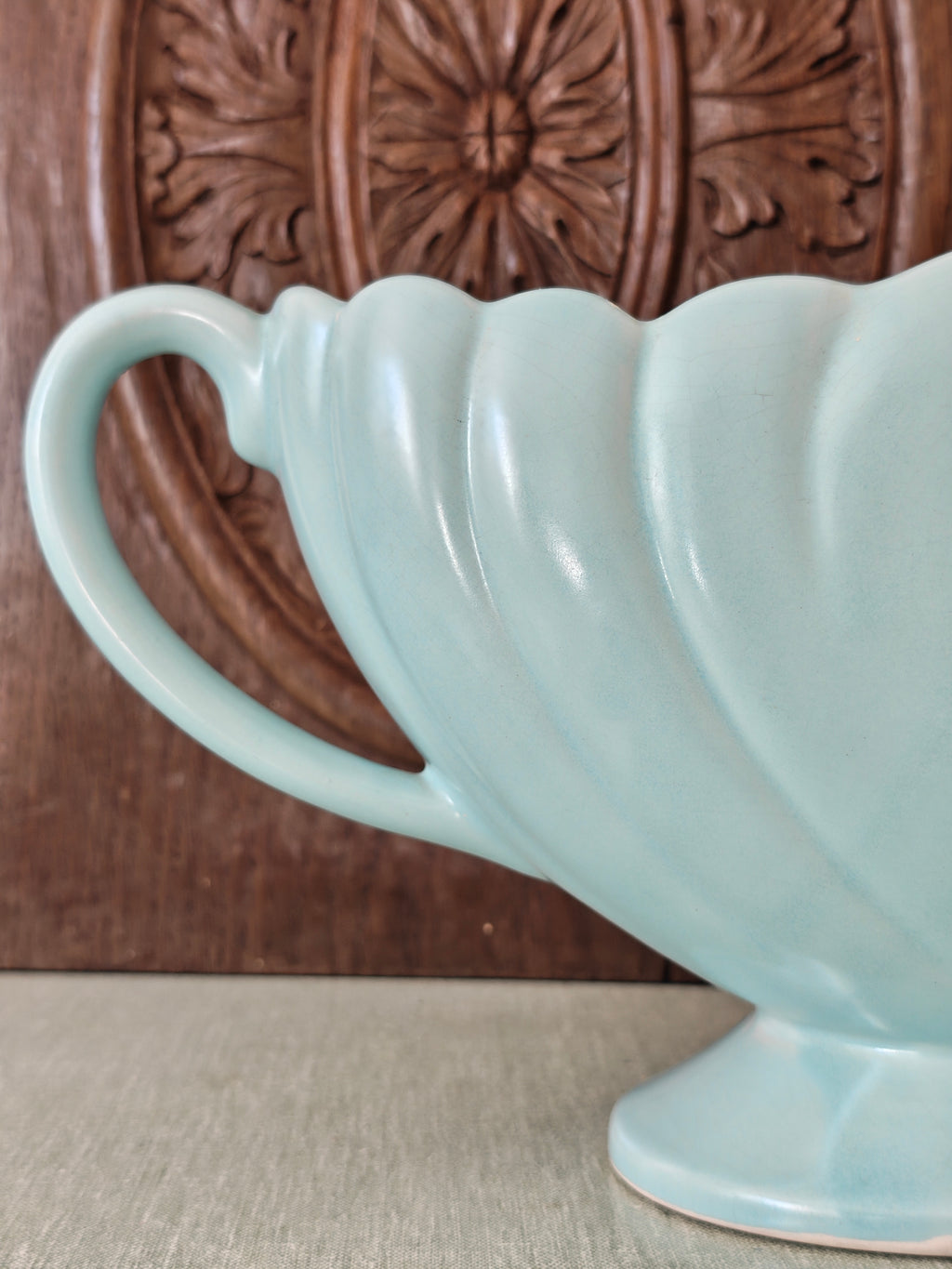 Close up view of the handle of a large pale blue mantle vase with fluted form 