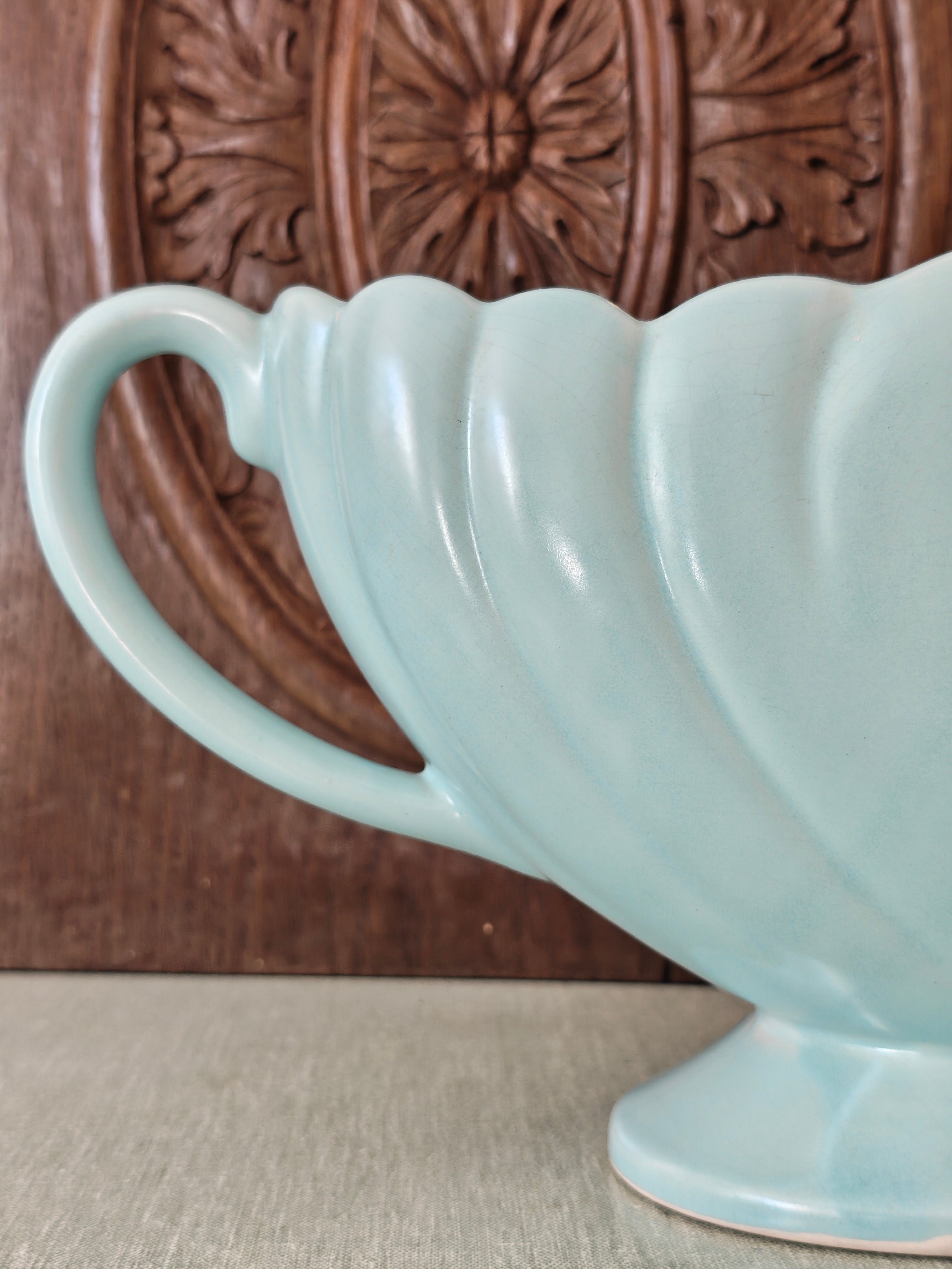 Close up view of the handle of a large pale blue mantle vase with fluted form 