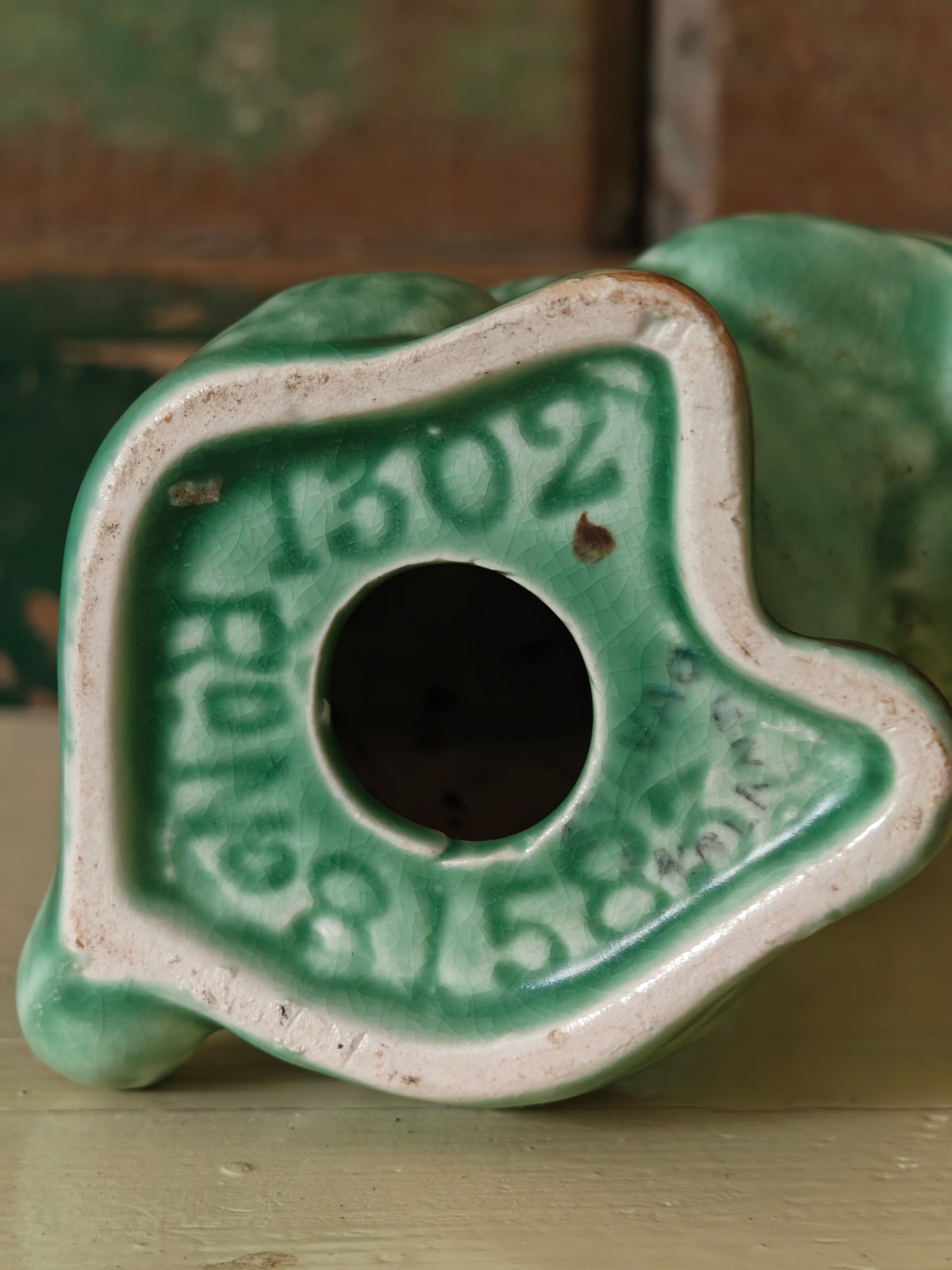 Close-up of the base of a vintage green ceramic figurine, showing the number 1302 and the Sylvac back stamp