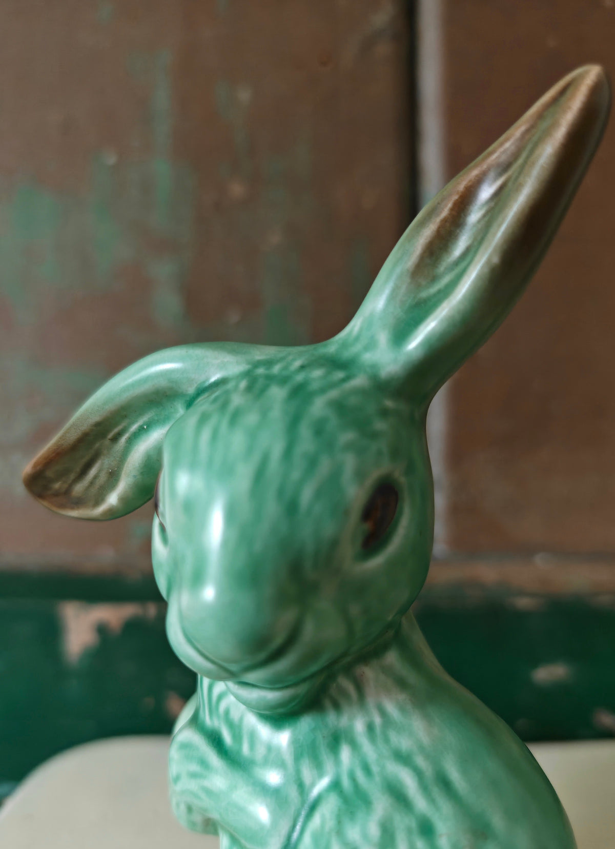 Close-p of the face of a green glazed ceramic rabbit figurine