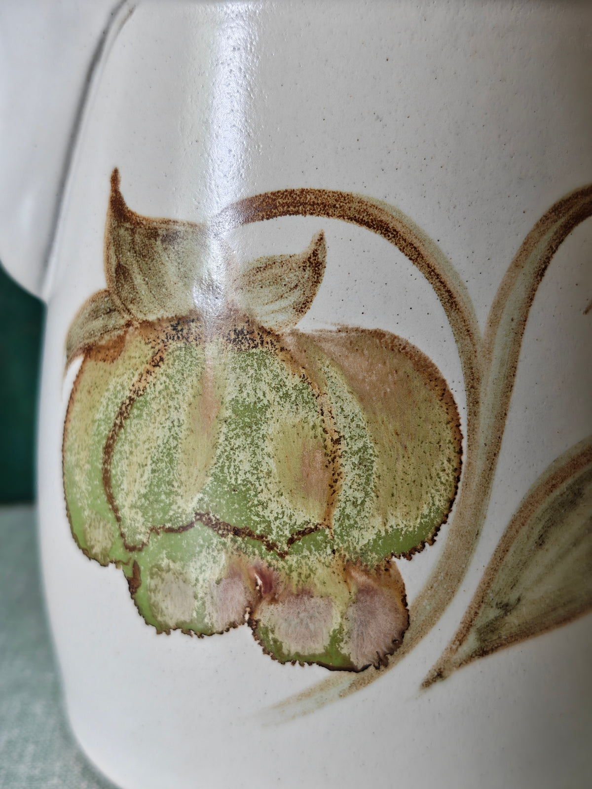 Close up of a flower decoration on the side of a ceramic pot.