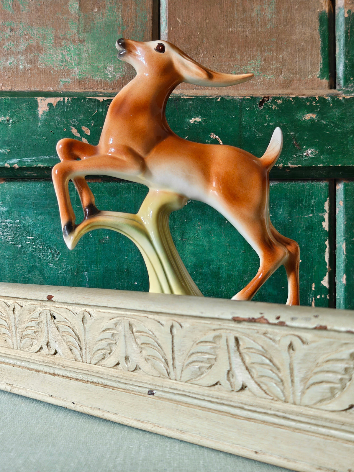 A vintage ceramic deer figurine in a rearing pose, featuring a glossy brown and cream body mounted on a pale green base.