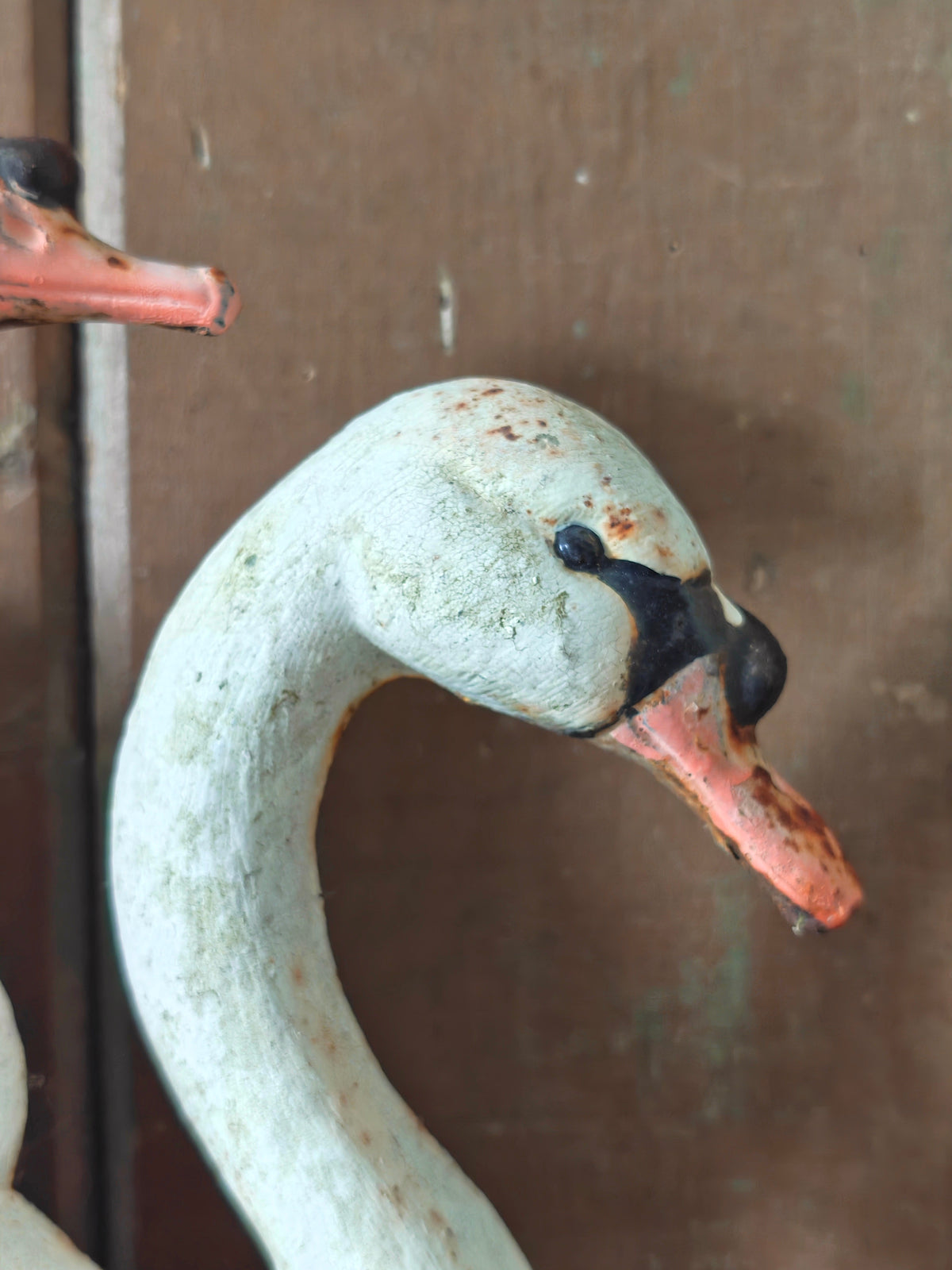 A close-up of a cast iron swan figurine showing the head and neck with pinkish beak and black detail.