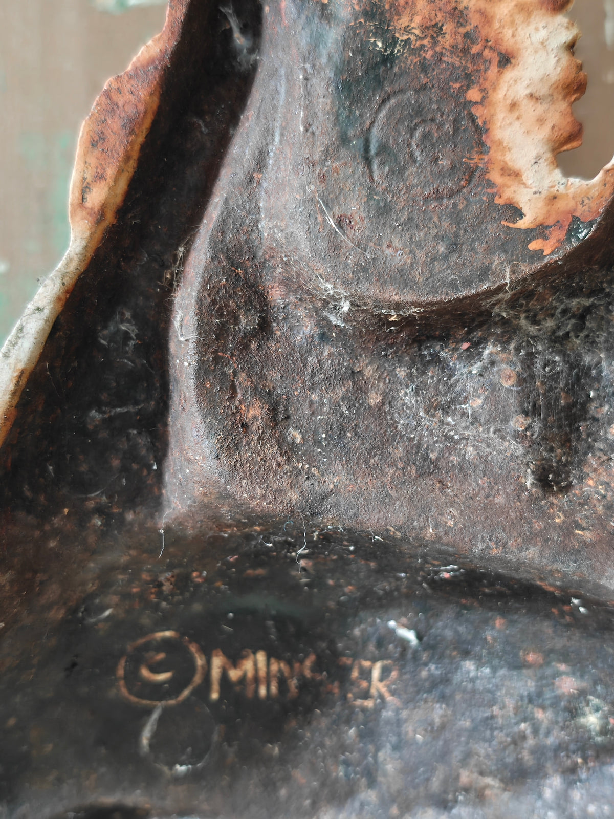 Reverse side of a cast iron doorstop with the brand name Minster hand painted