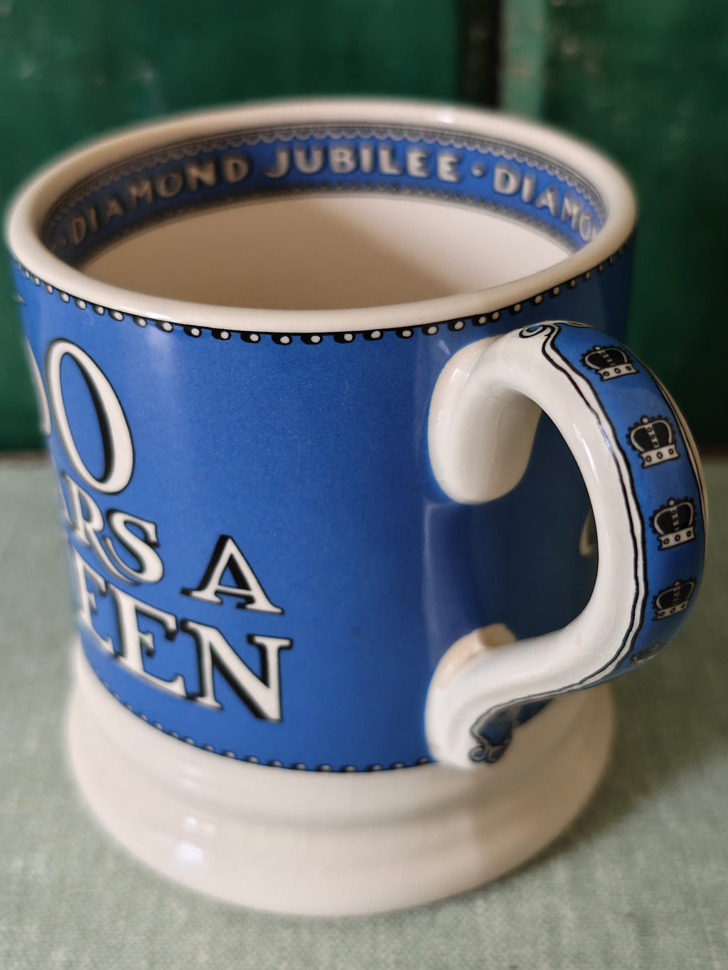 A blue and white ceramic mug with 'Diamond Jubilee' text and crown motifs.