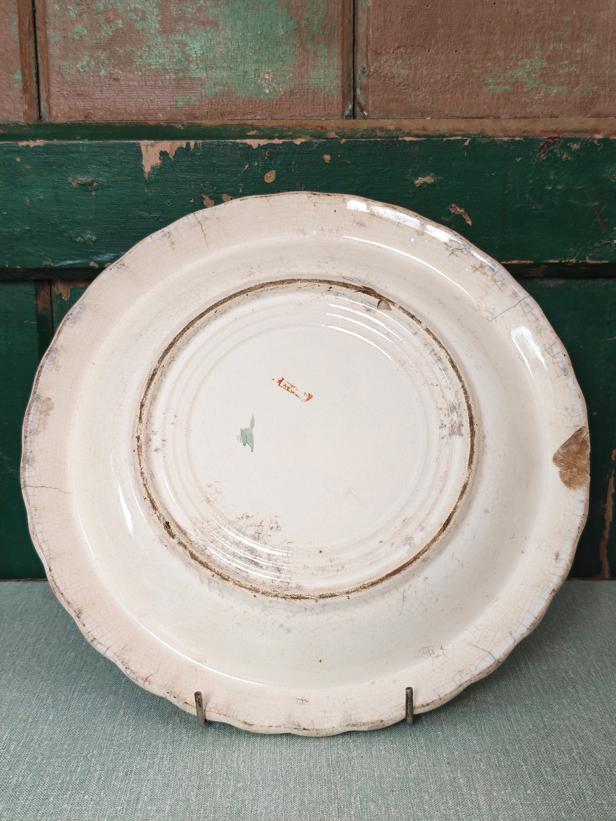 Back view of an off-white ceramic plate with crackled glaze and a chipped edge
