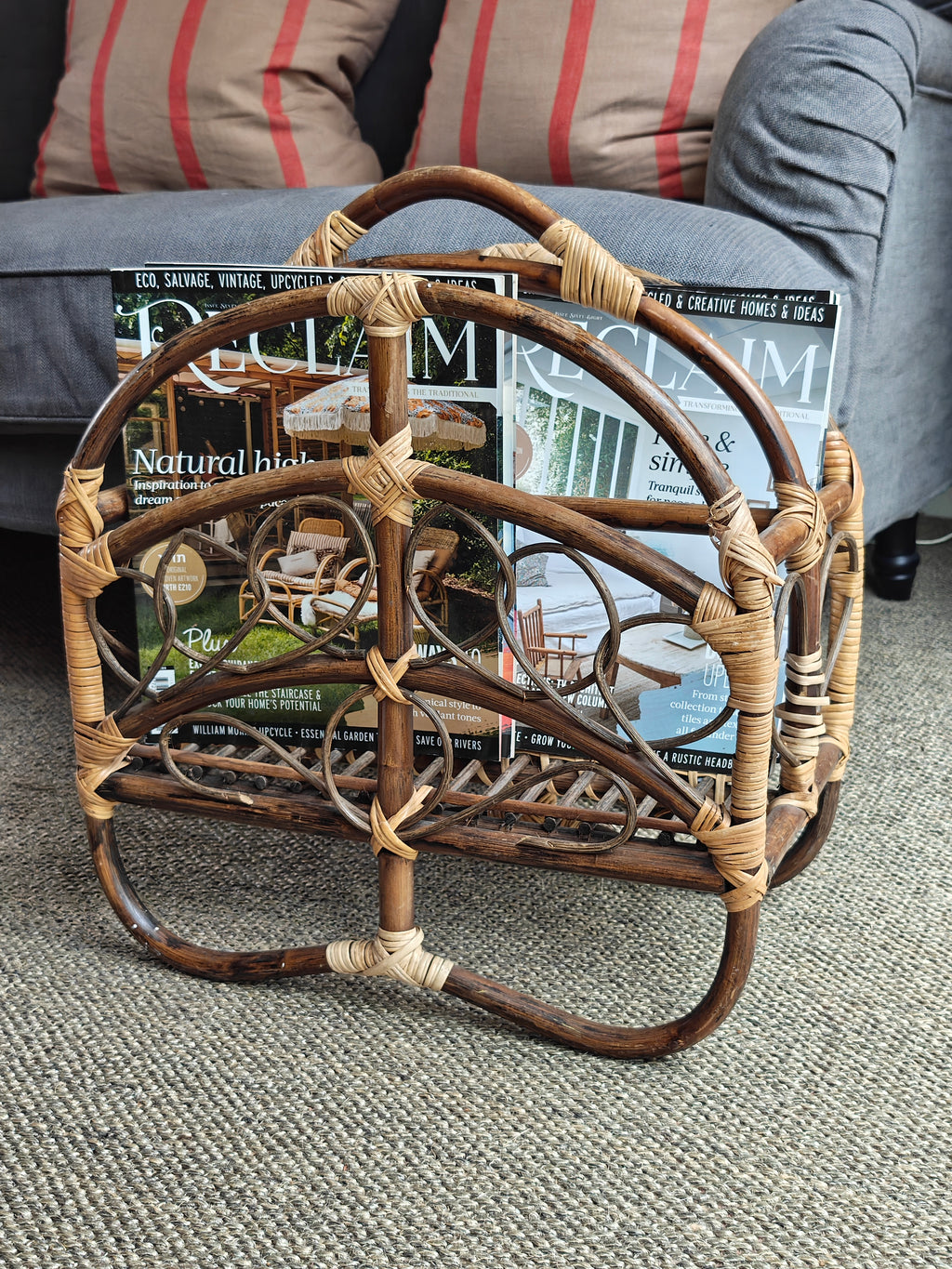 A vintage bamboo and rattan magazine rack with a rounded dome shape, featuring brown wooden frame and woven bamboo accents.