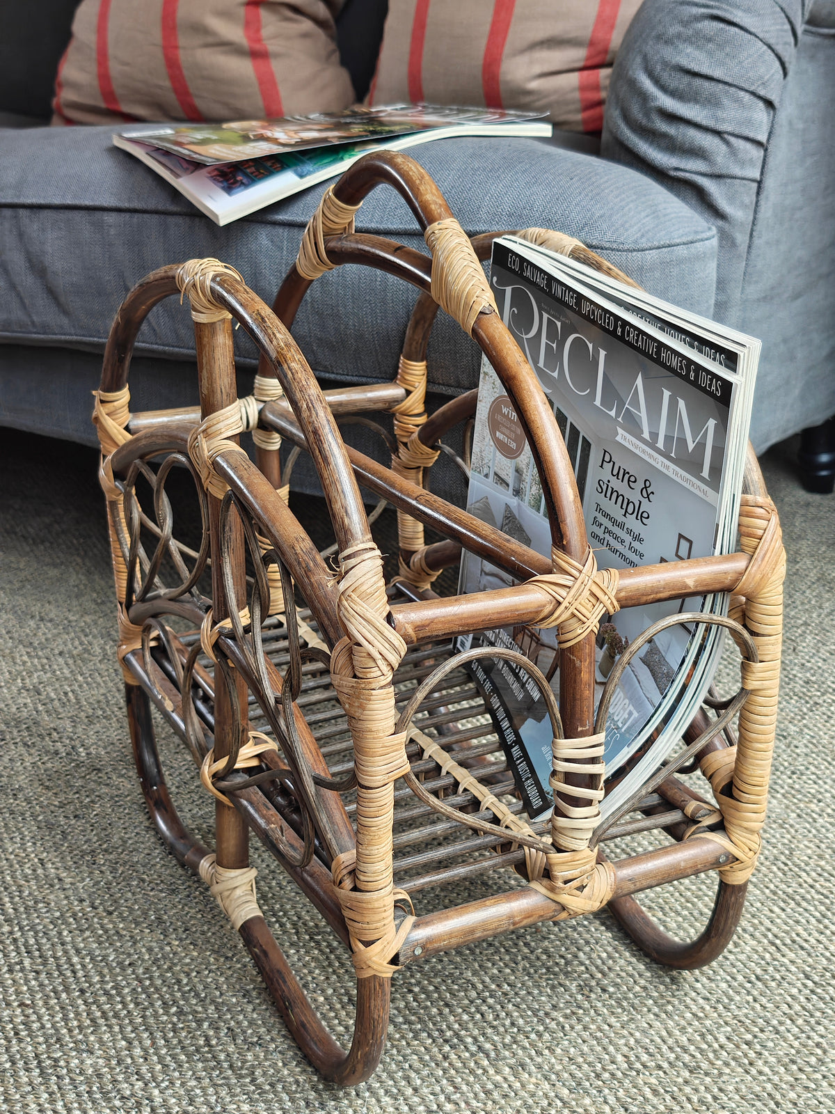 A vintage bamboo and rattan magazine rack with a rounded dome shape, featuring brown wooden frame and woven bamboo accents.