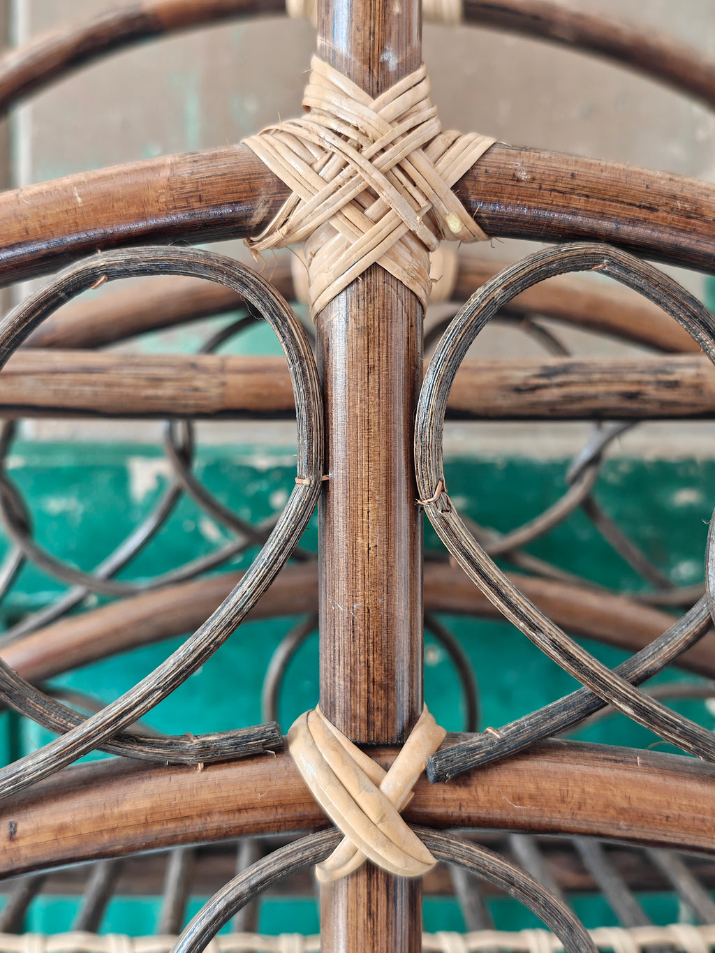 Close up of a vintage bamboo and rattan magazine rack with a rounded dome shape, featuring brown wooden frame and woven bamboo accents.