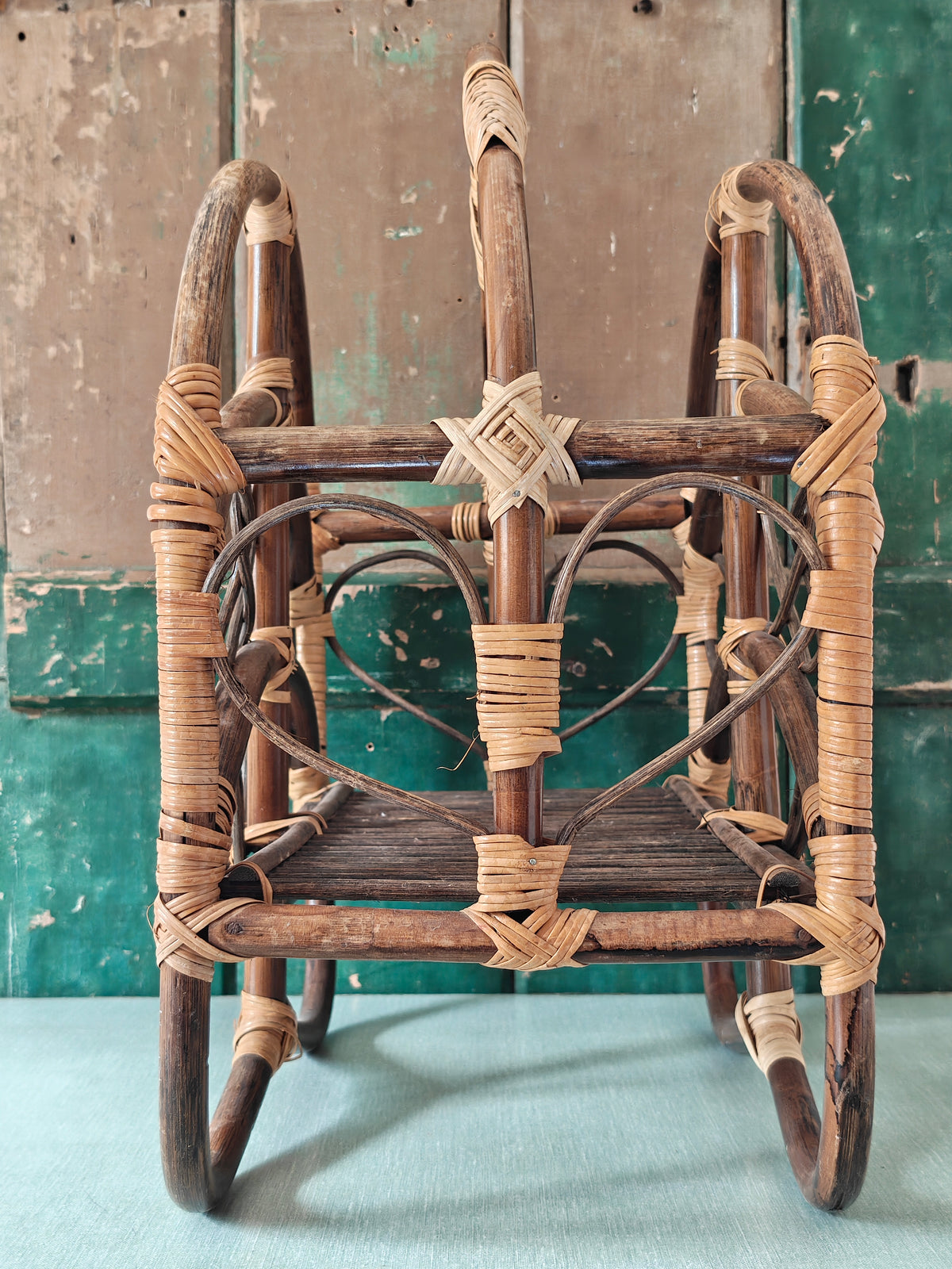 A vintage bamboo and rattan magazine rack with a rounded dome shape, featuring brown wooden frame and woven bamboo accents.