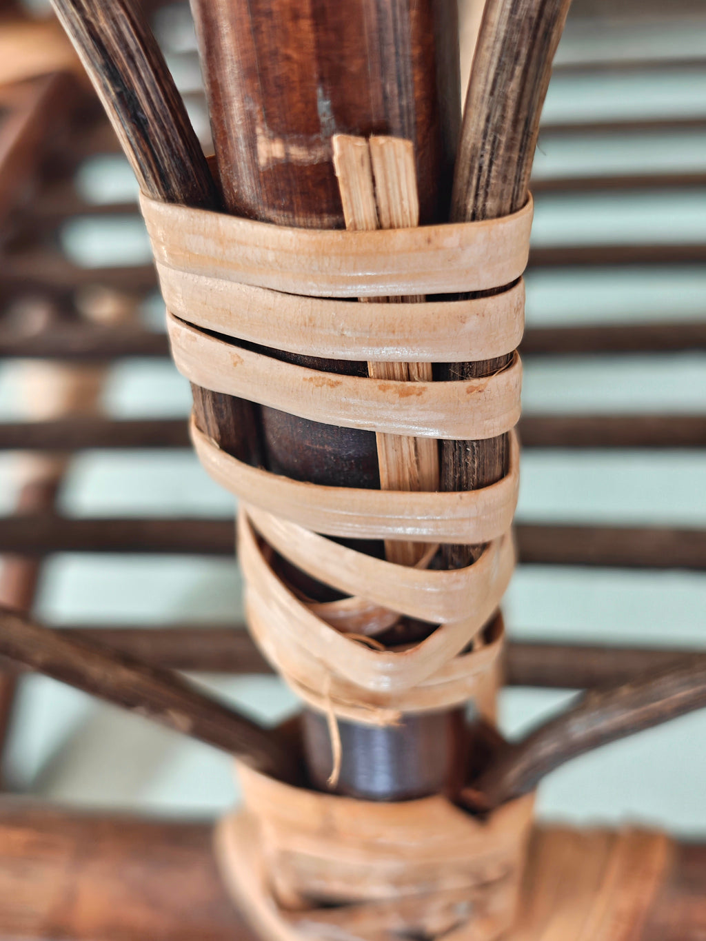 Close-up of a vintage bamboo and rattan magazine rack with a rounded dome shape, featuring brown wooden frame and woven bamboo accents.