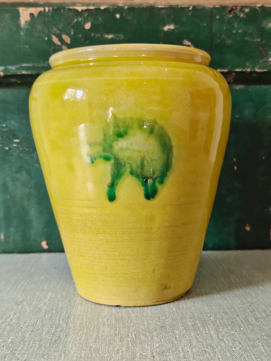 A yellow glazed ceramic jar with a green drip glaze design