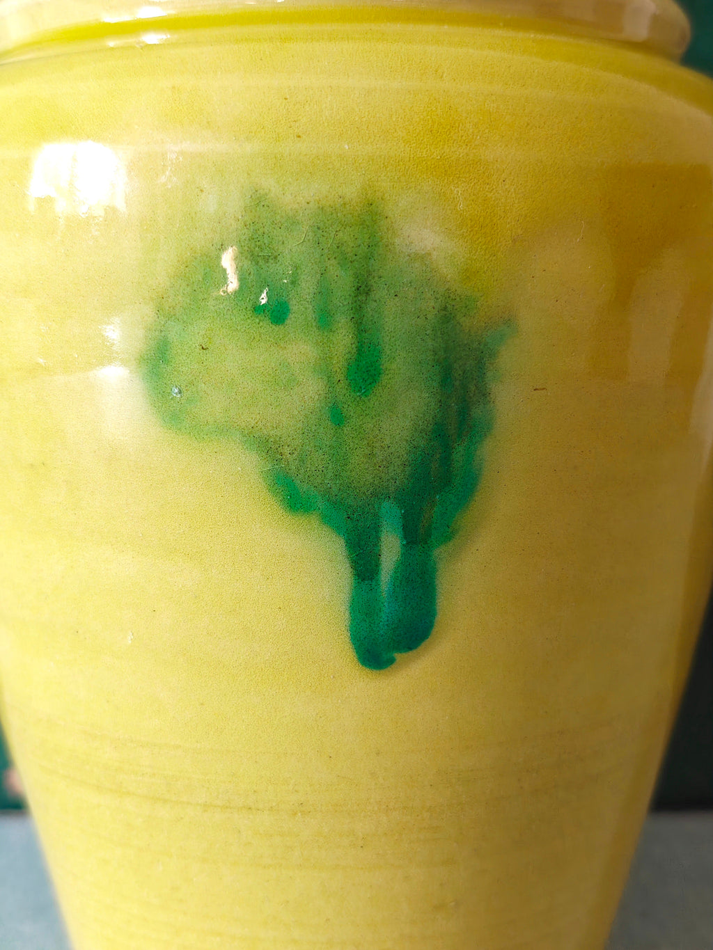 Close-up of a yellow glazed ceramic jar with a green drip glaze design