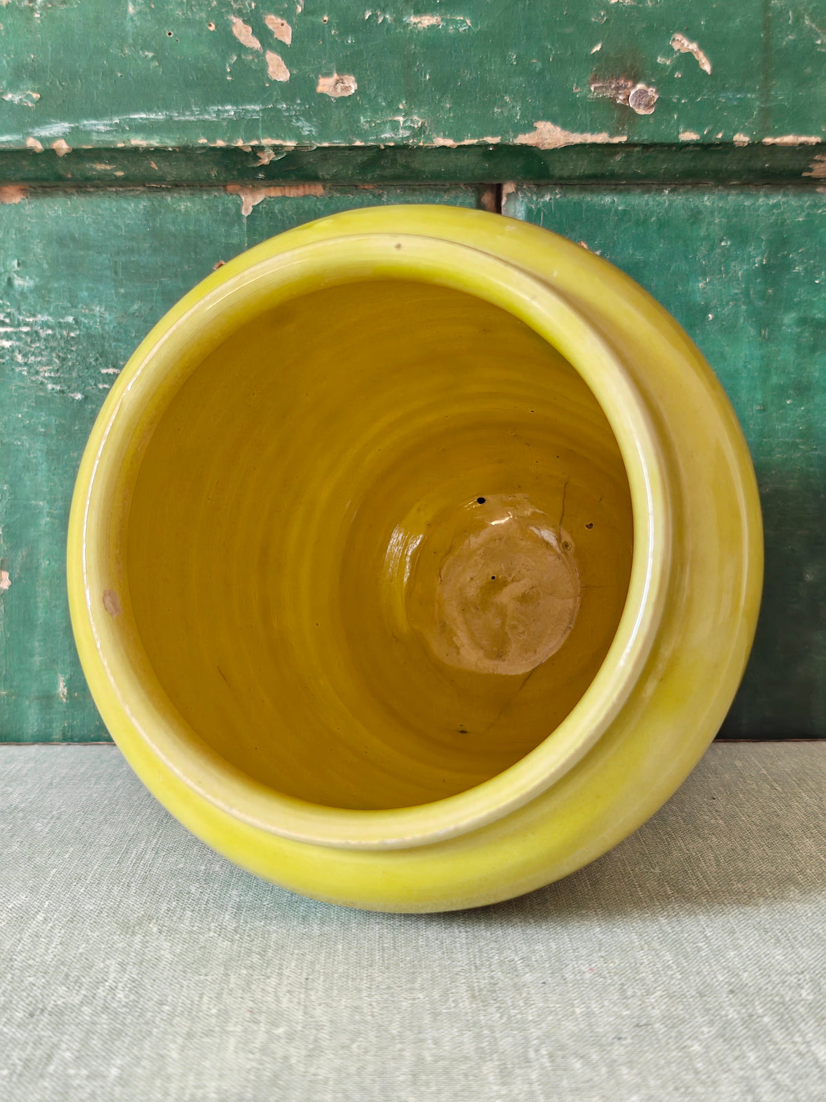 Interior view of a yellow glazed ceramic jar with a green drip glaze design