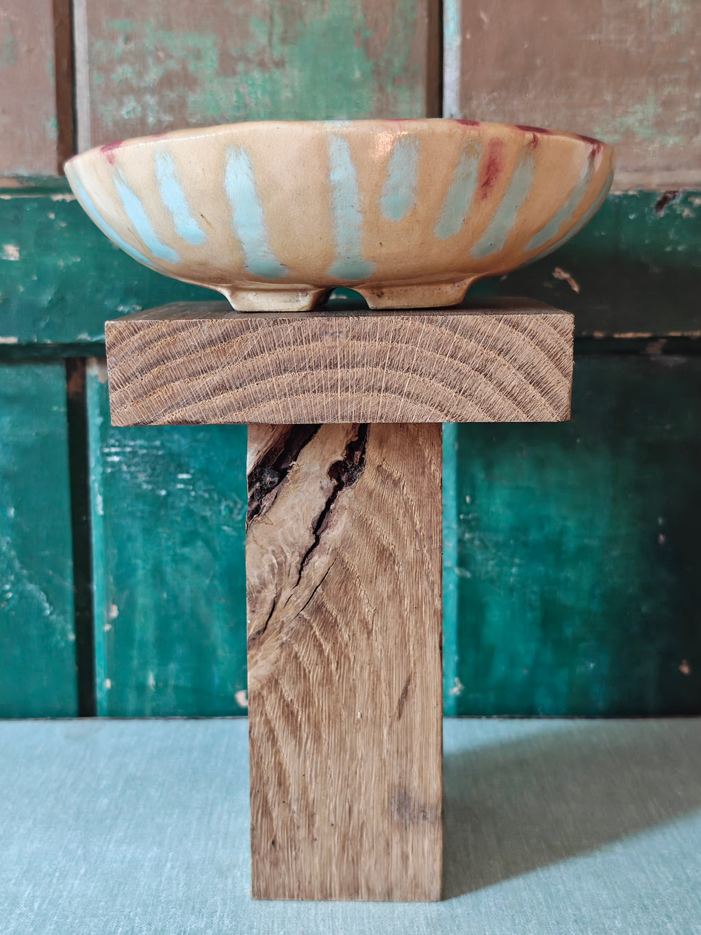 Side view of a handmade ceramic bowl with a beige glaze and abstract drip glaze pattern in blue, red and gold.