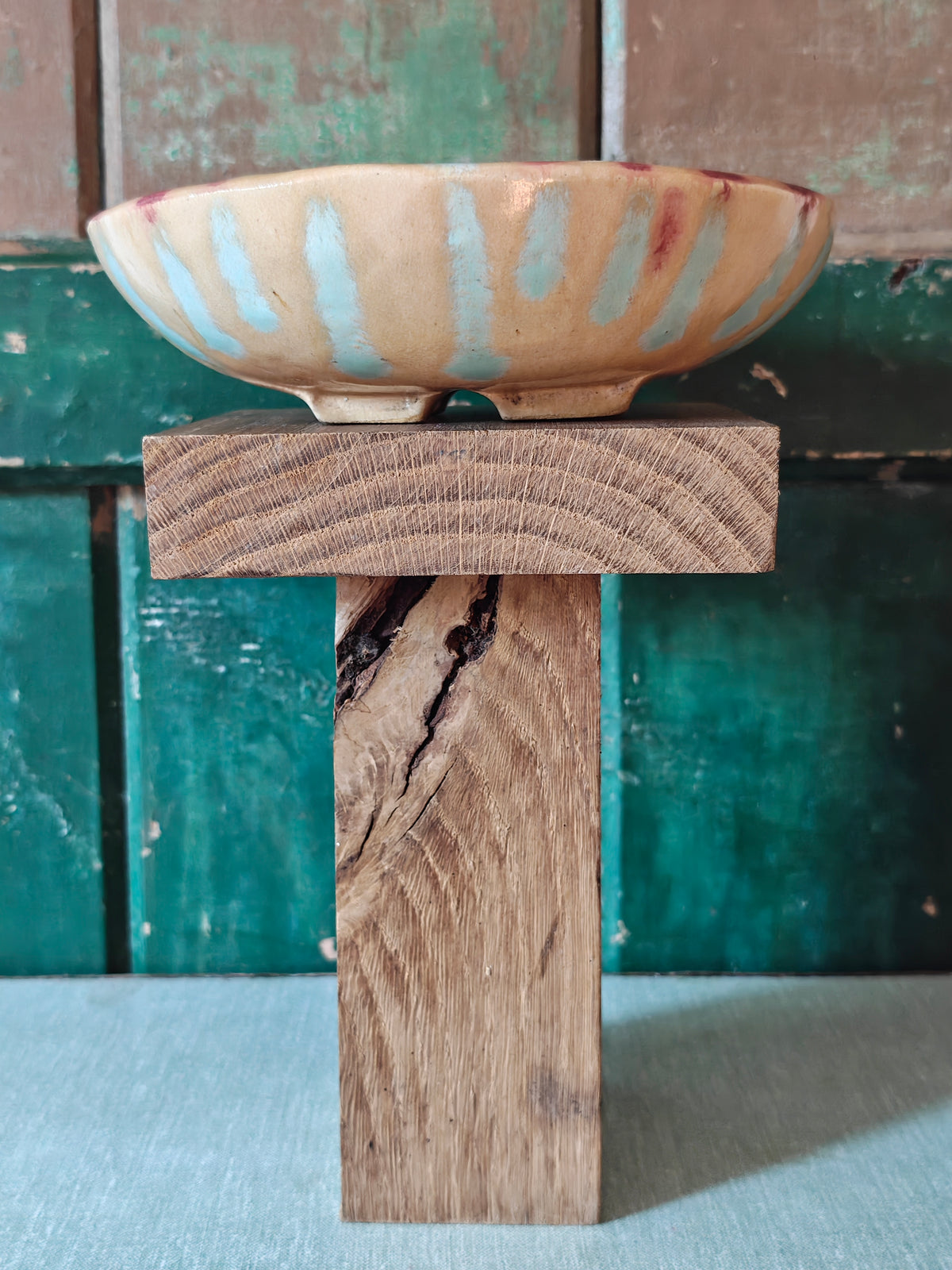 Side view of a handmade ceramic bowl with a beige glaze and abstract drip glaze pattern in blue, red and gold.