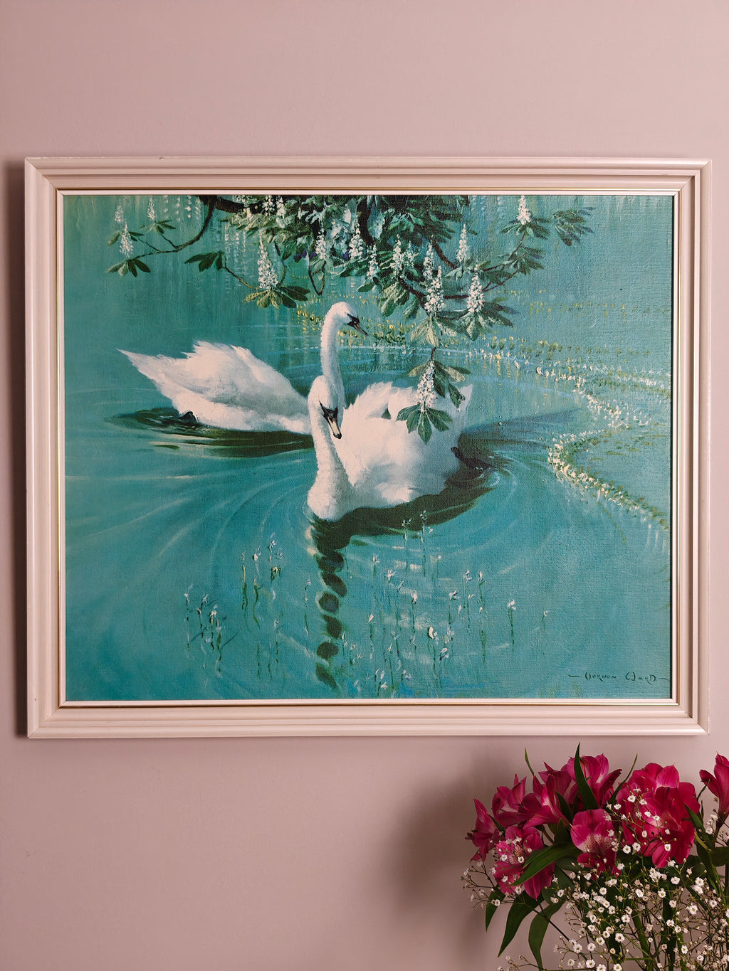 A framed painting of two white swans swimming in a turquoise pond under hanging green leaves and white flowers.
