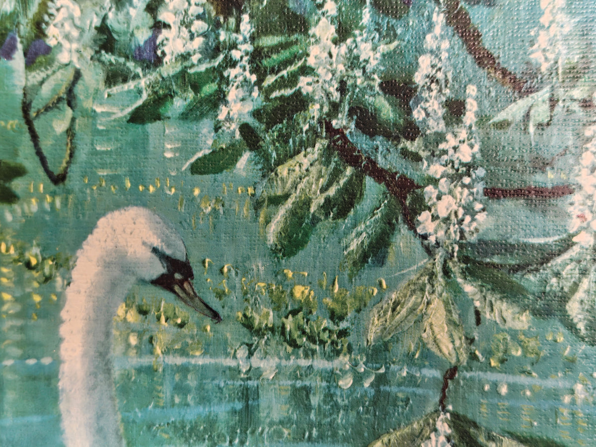 A close-up of a print on board featuring a white swan in profile against a teal and green water scene with leafy branches and white blossoms.