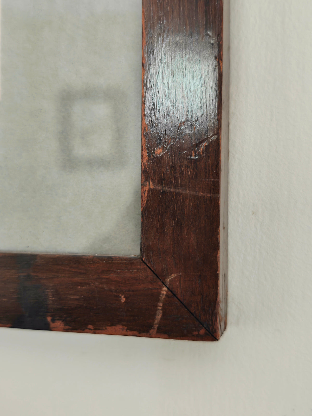 Close-up of a dark brown wooden picture frame corner with a distressed finish.
