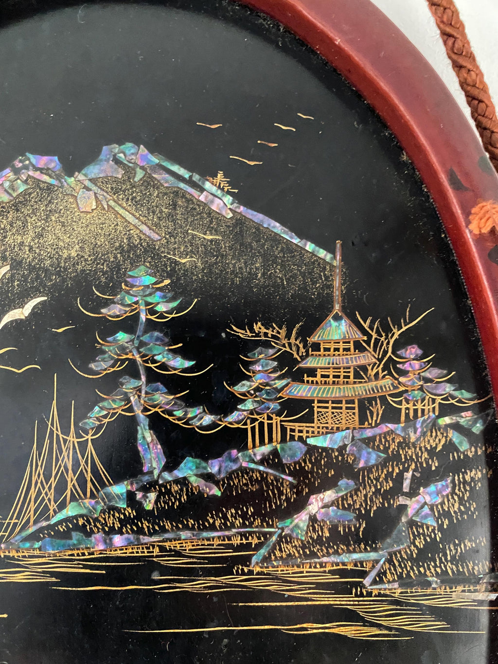 Detail of a decorative panel with gold and iridescent elements, featuring a pagoda and landscape.