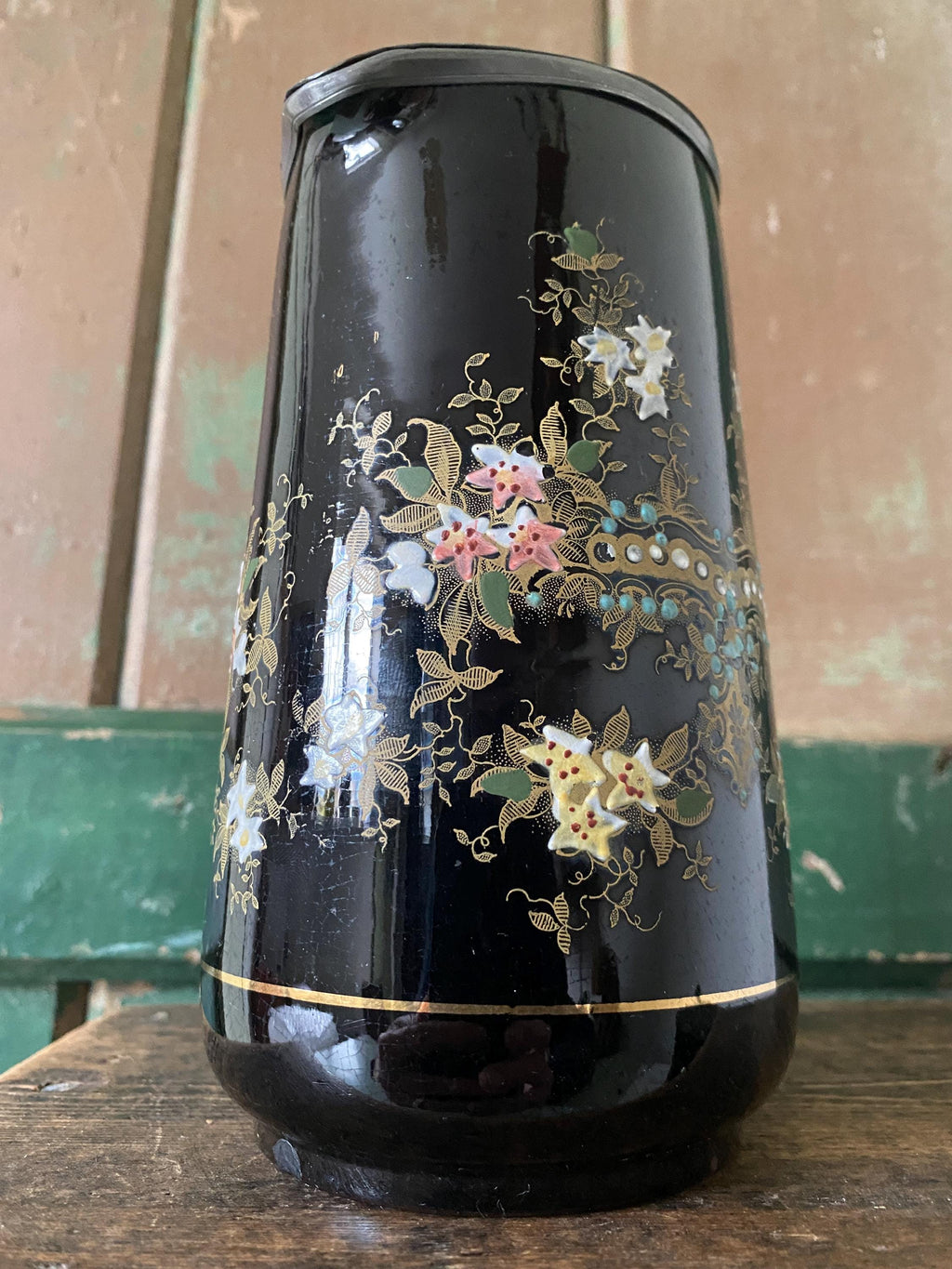 Decorative black jug with floral patterns and a metal lid 