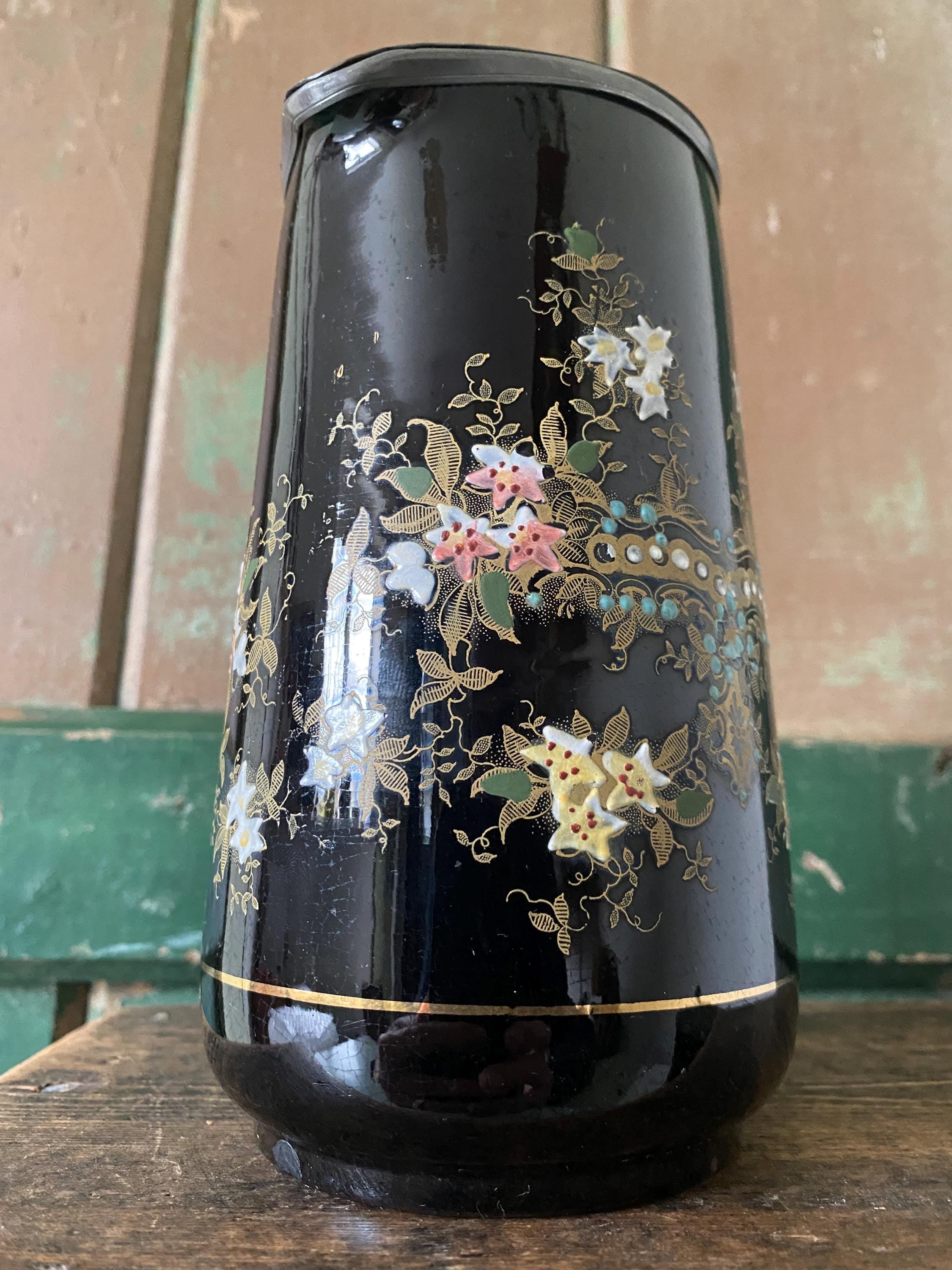 Decorative black jug with floral patterns and a metal lid 