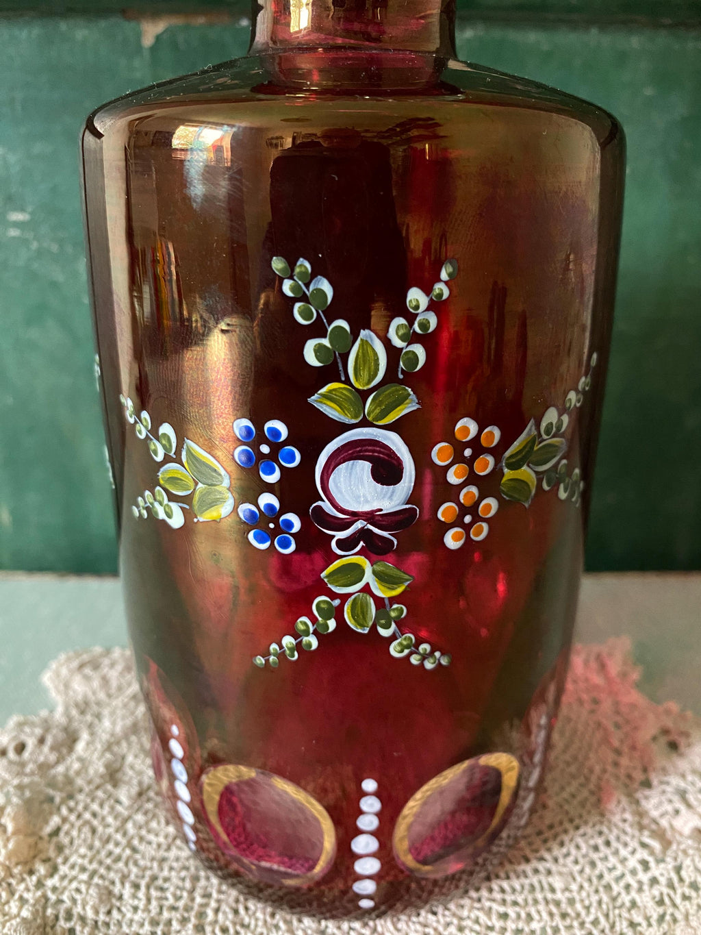 Decorative red glass decanter with hand painted flower decoration
