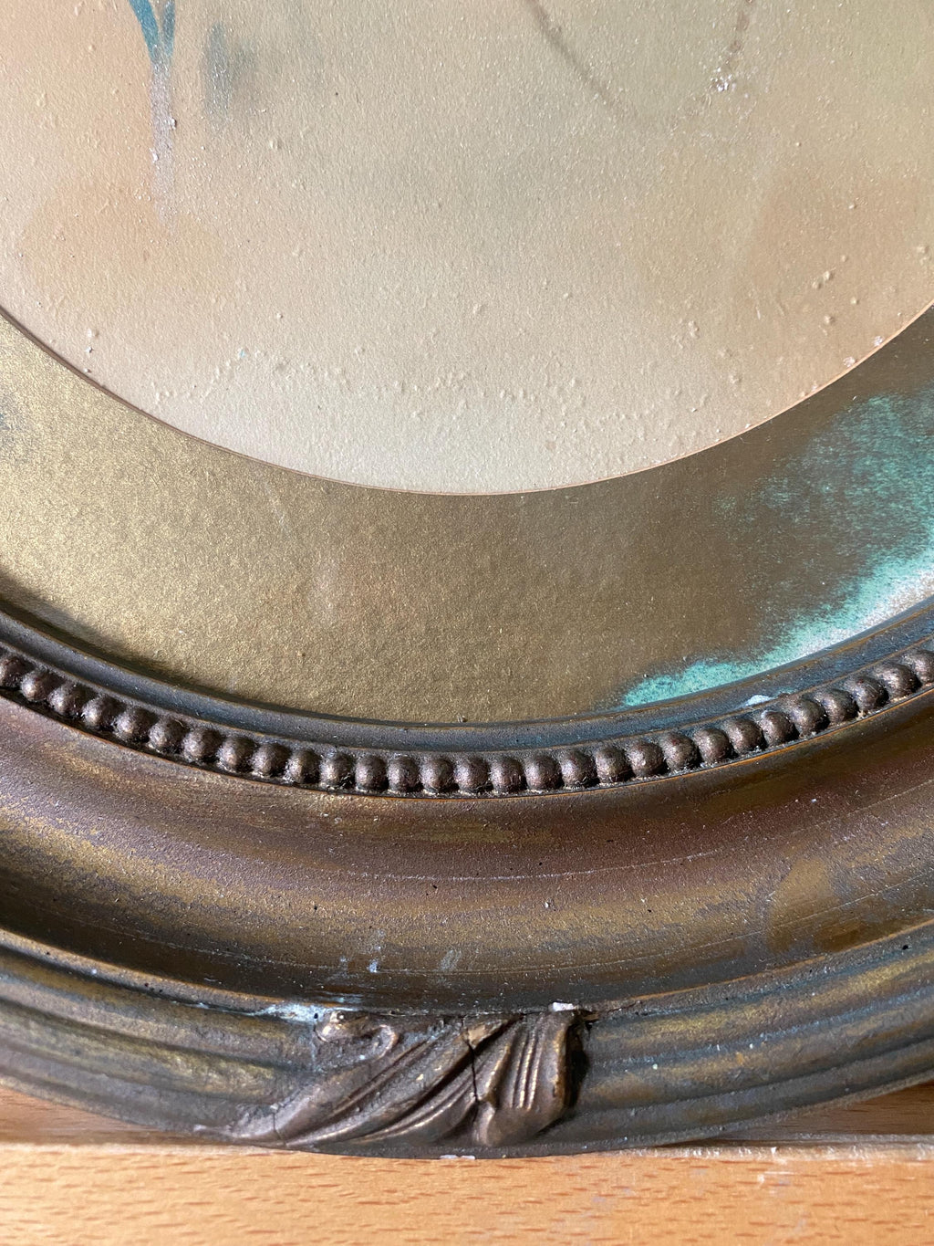 Close-up of part of an oval gold frame and picture mount