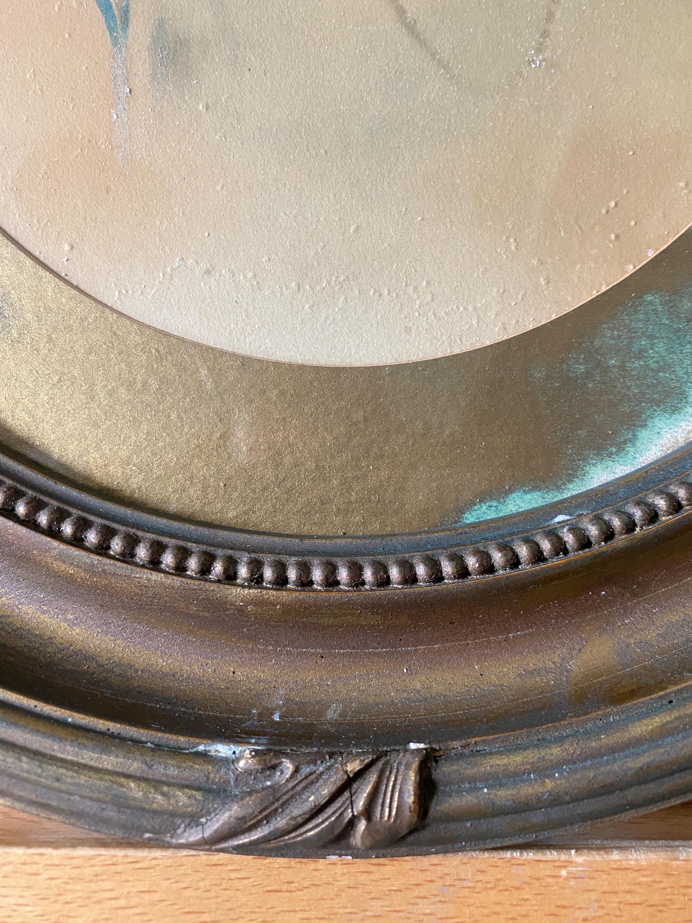 Close-up of part of an oval gold frame and picture mount