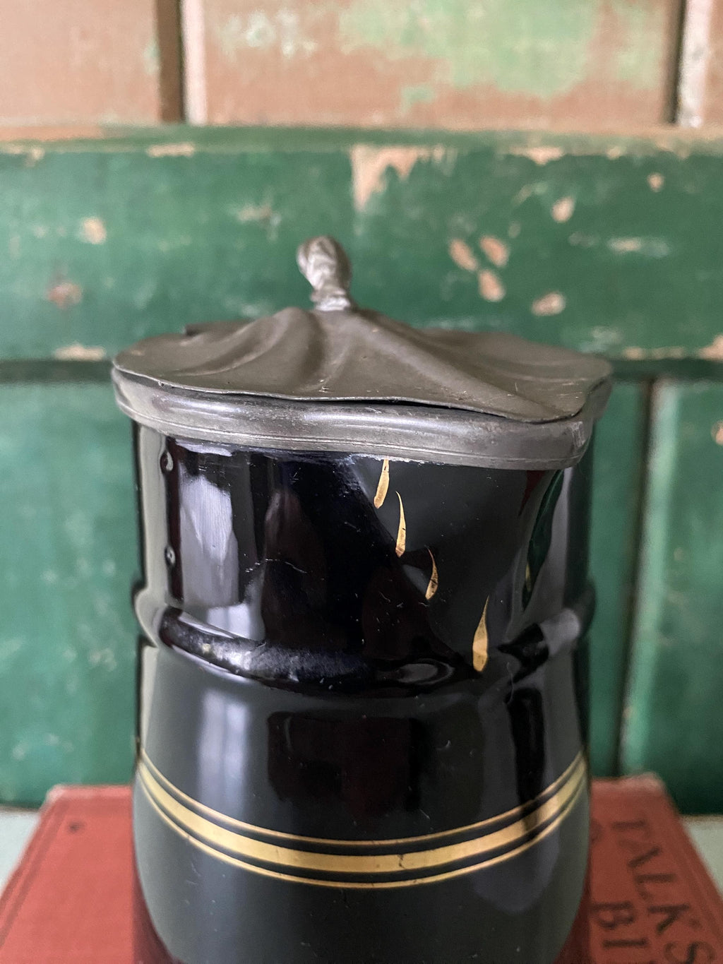 Black ceramic pitcher with gold stripe and hinged metal lid