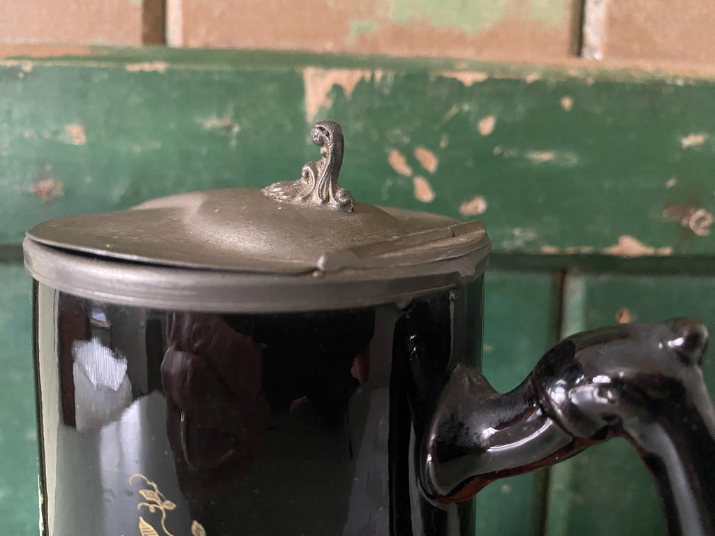 Close-up of the metal lid on a decorative black jug 