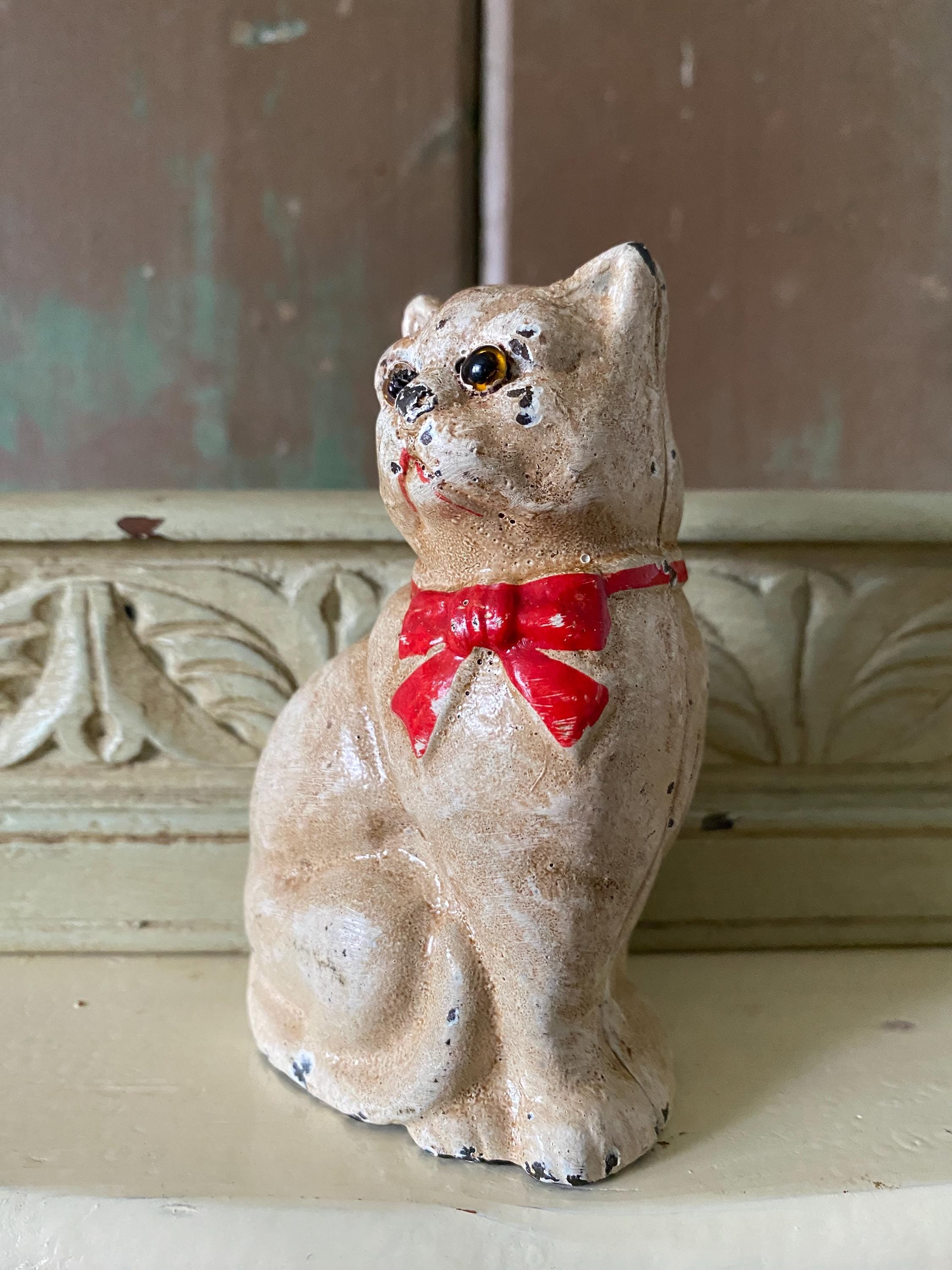 Small metal figurine of a white cat  with a red bow