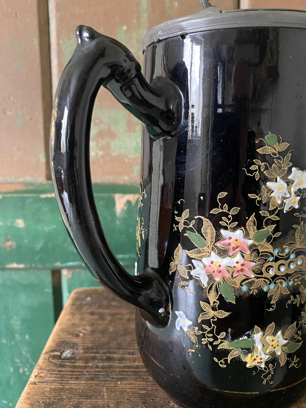 Close-up of the handle and floral decoration on a black jug 