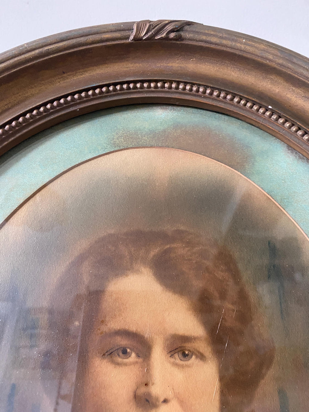 Close-up of a vintage portrait of a woman in an oval gold frame