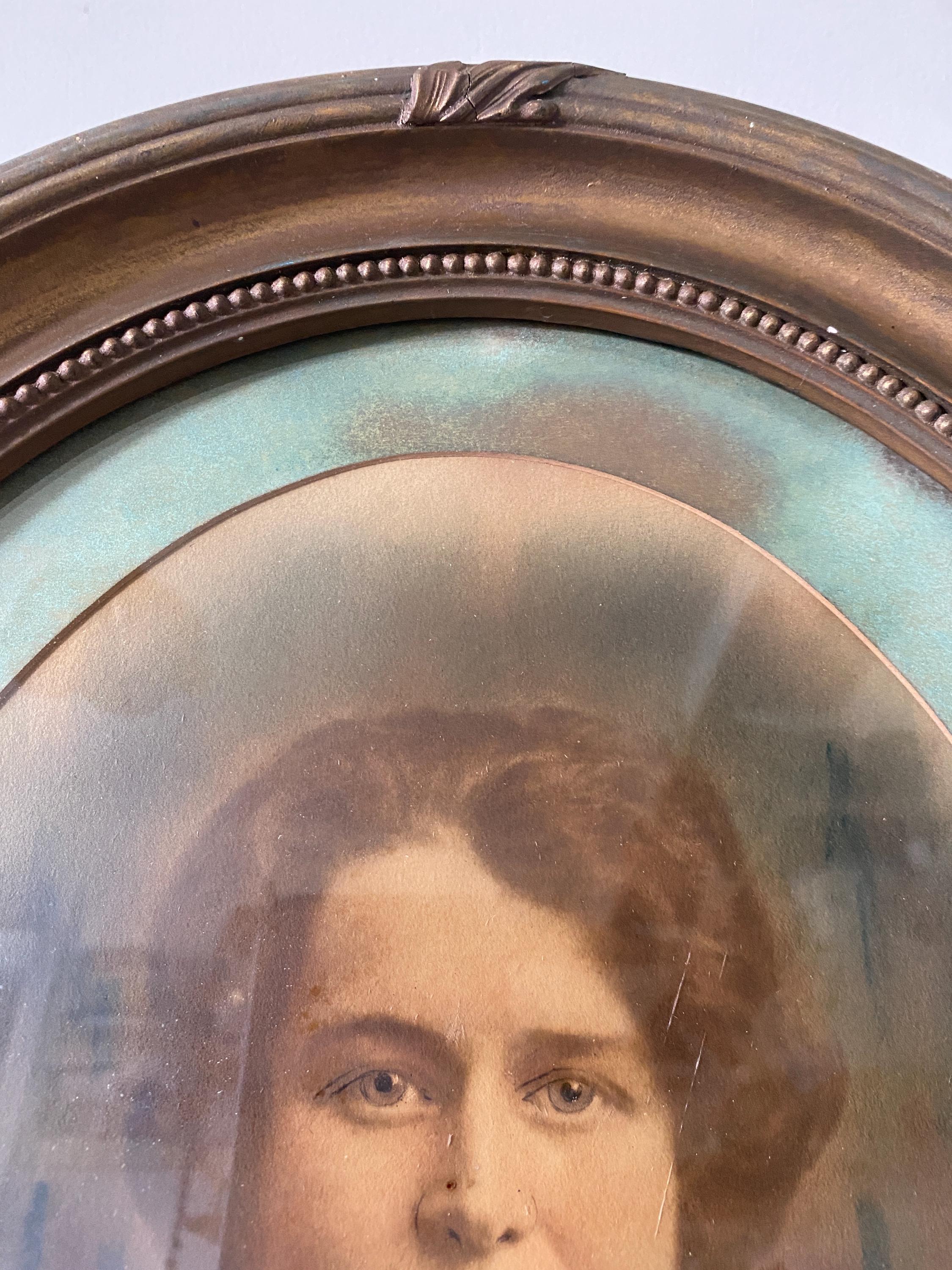 Close-up of a vintage portrait of a woman in an oval gold frame
