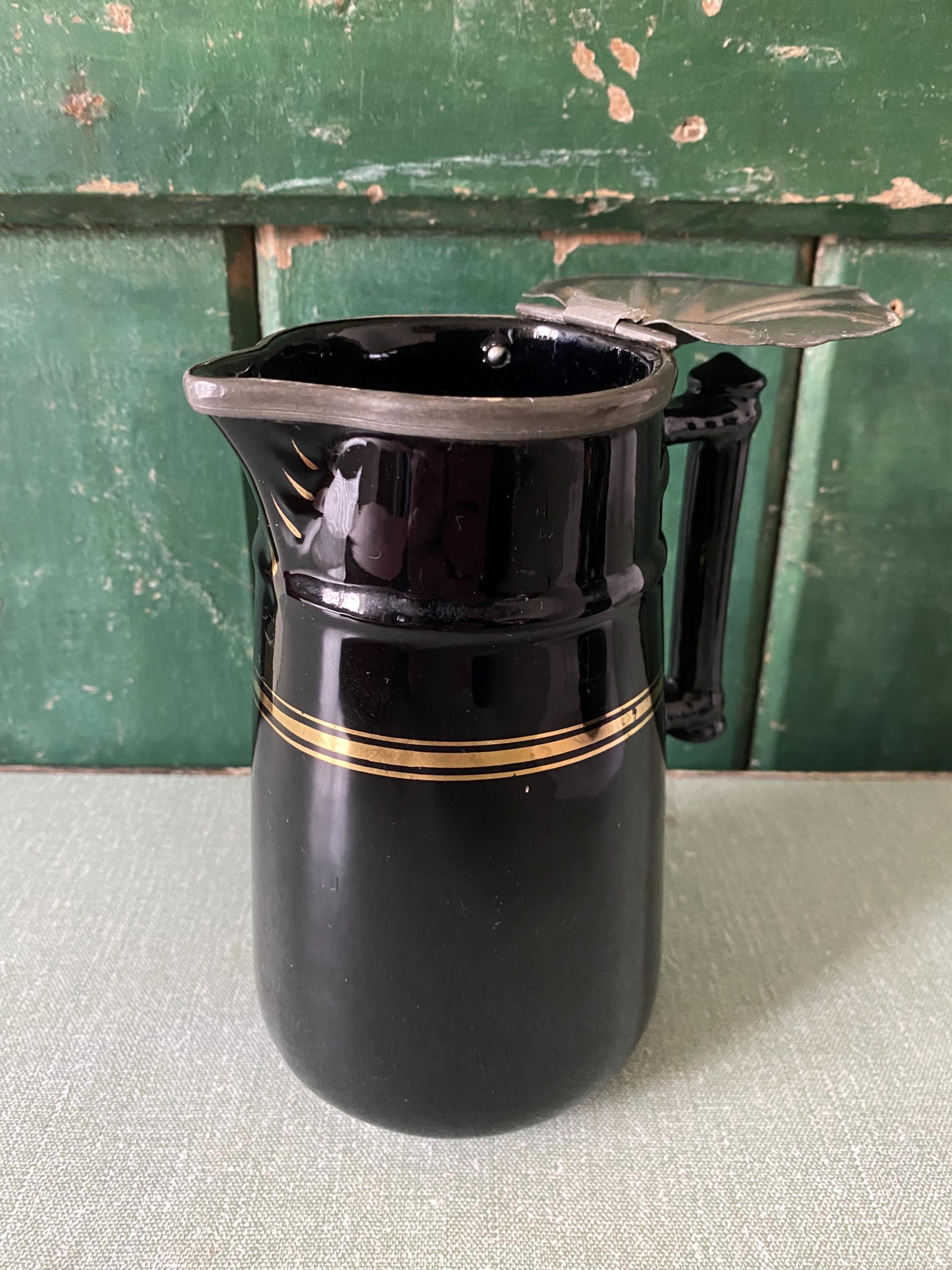 Black ceramic pitcher with gold stripe and hinged metal lid