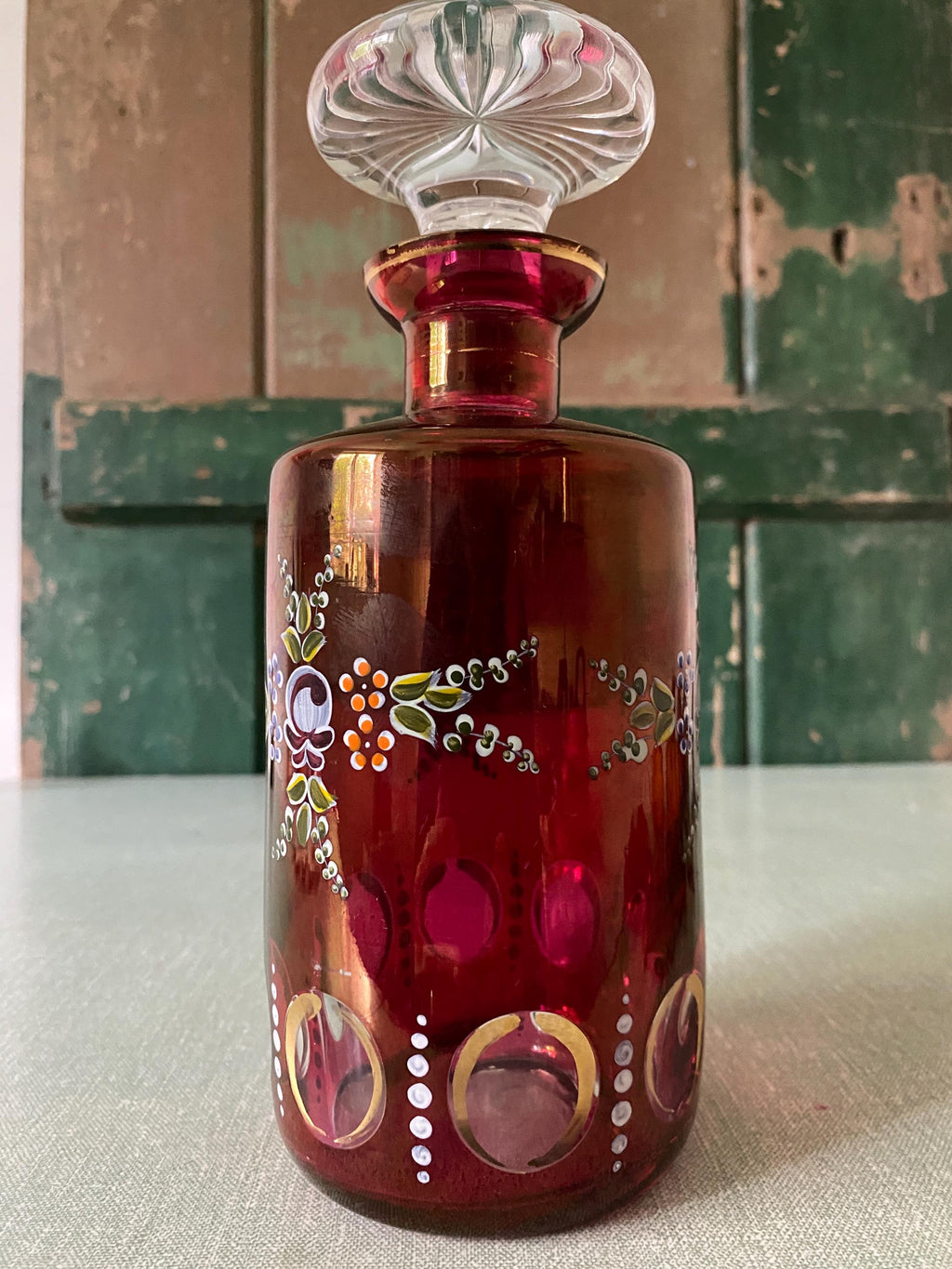 Decorative red glass decanter with intricate painted designs.