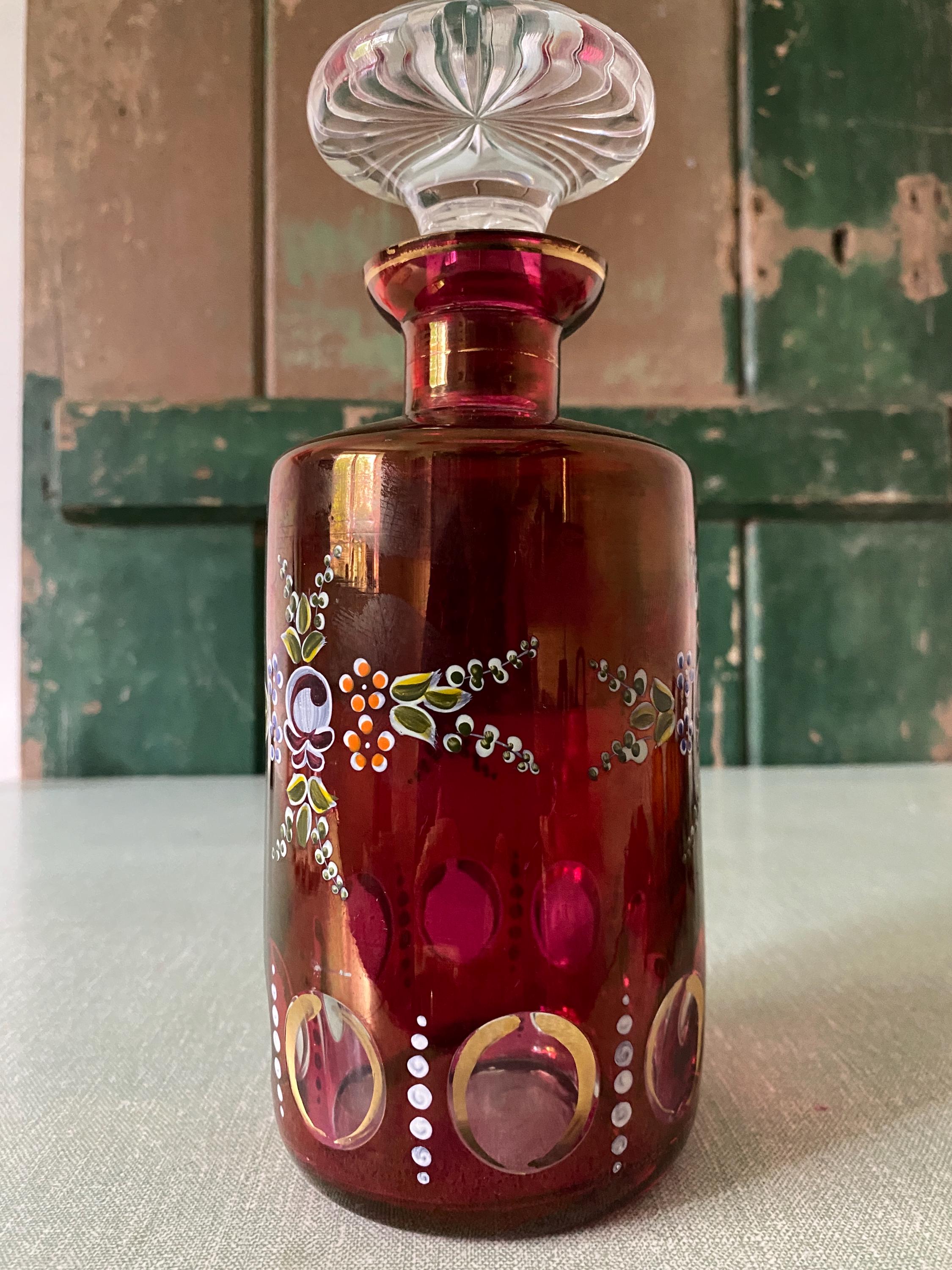 Decorative red glass decanter with intricate painted designs.