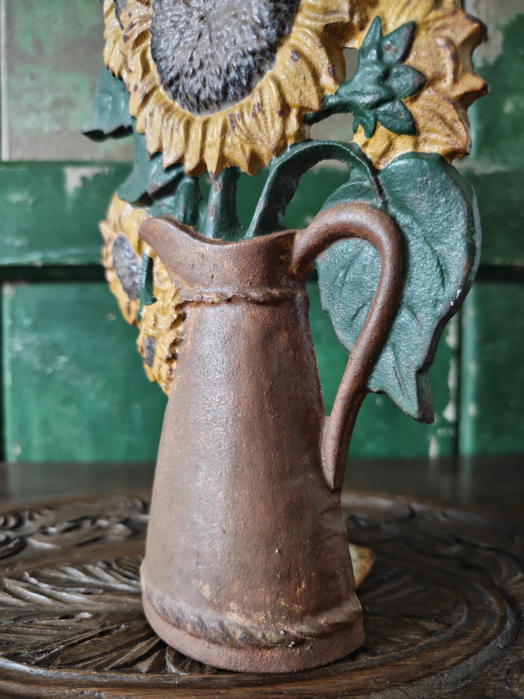 Decorative pitcher with sunflower design on a wooden surface