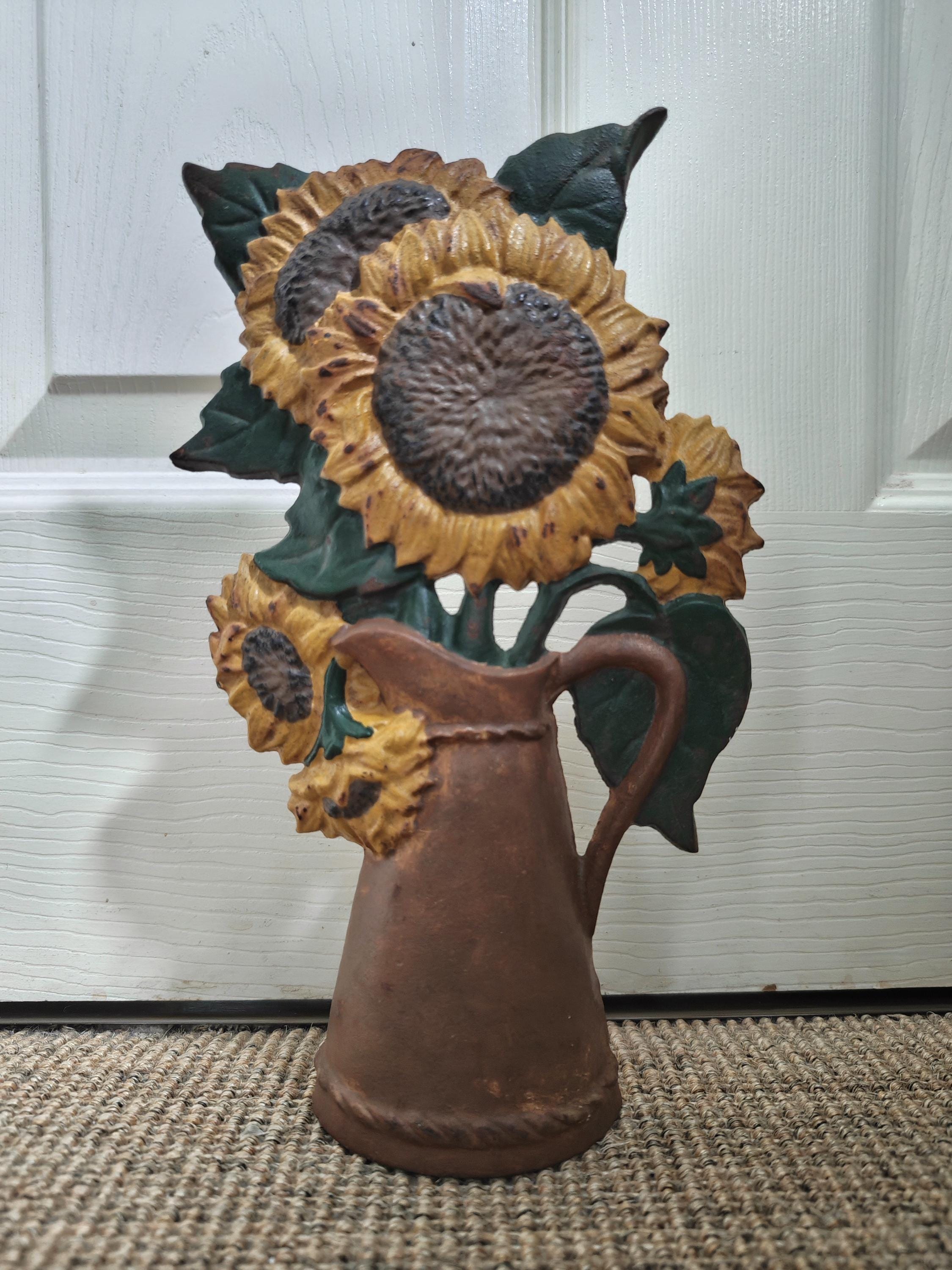 Decorative cast iron sunflower doorstop against a white door.