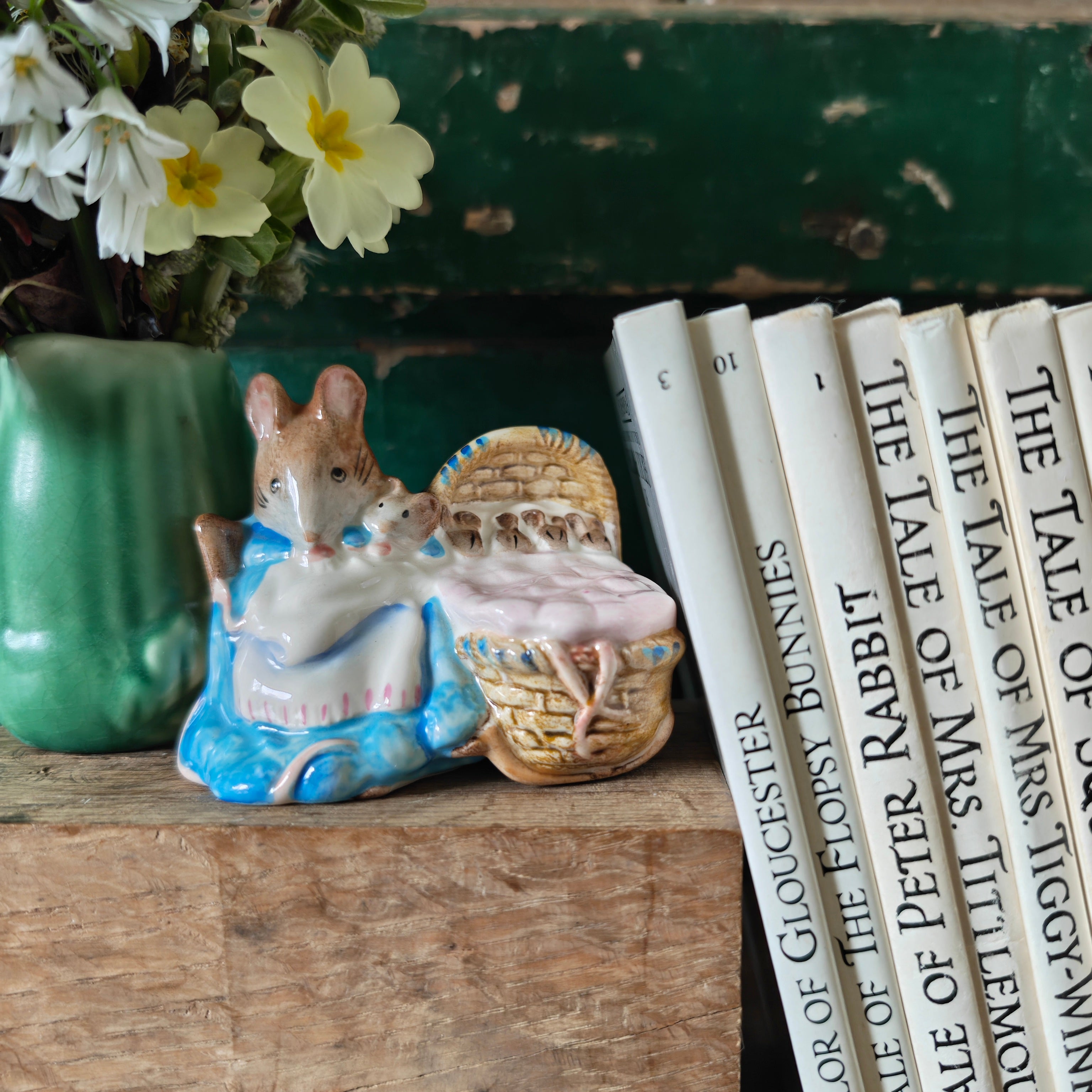 Decorative figurine of a mouse with a basket displayed on a shelf with books