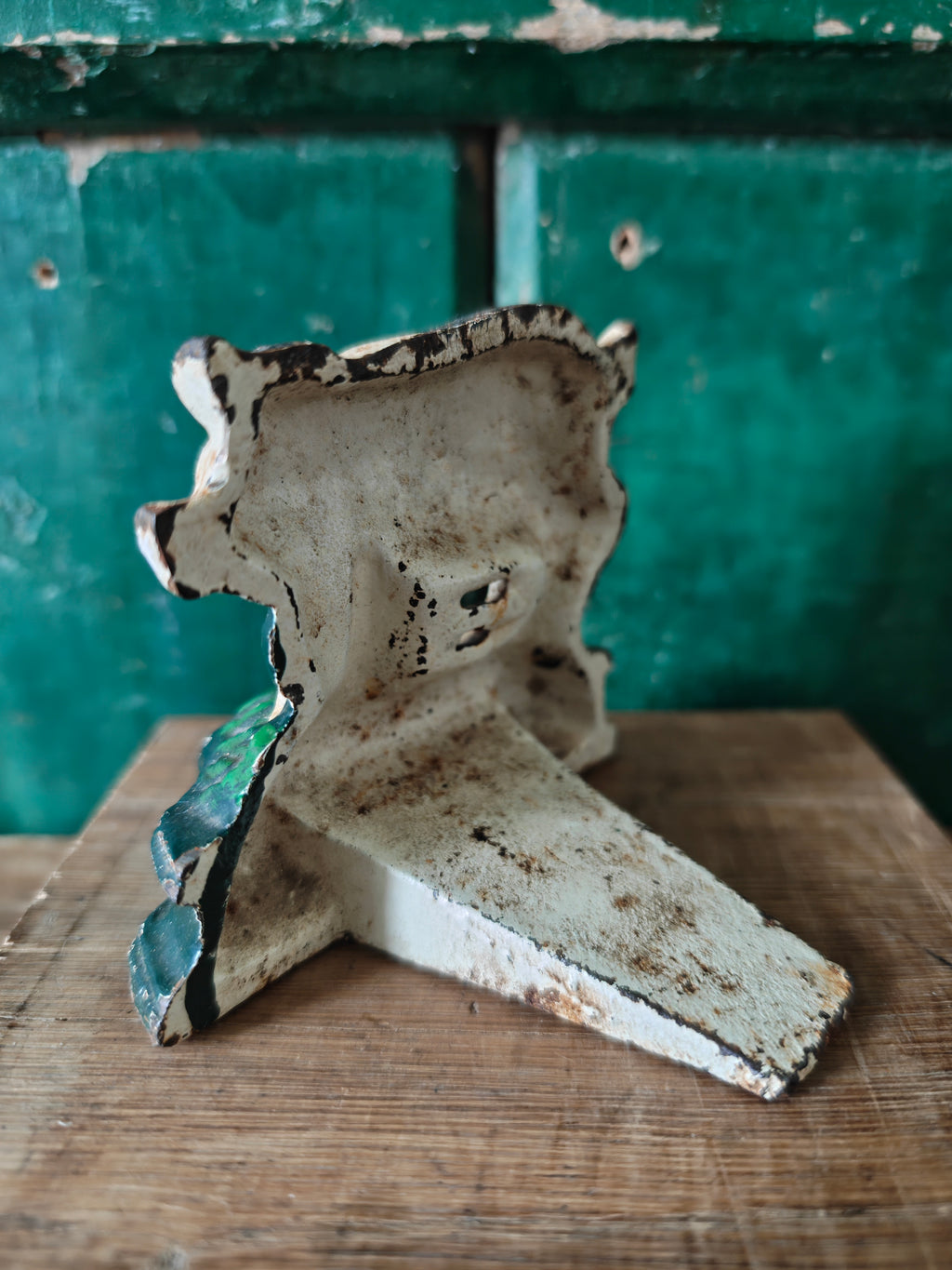 Back view of rustic metal doorstop with peeling paint 