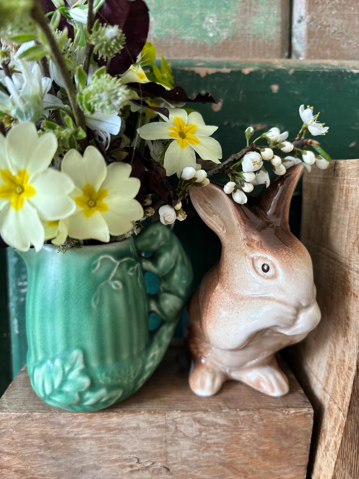 Ceramic rabbit figurine next to a green jug